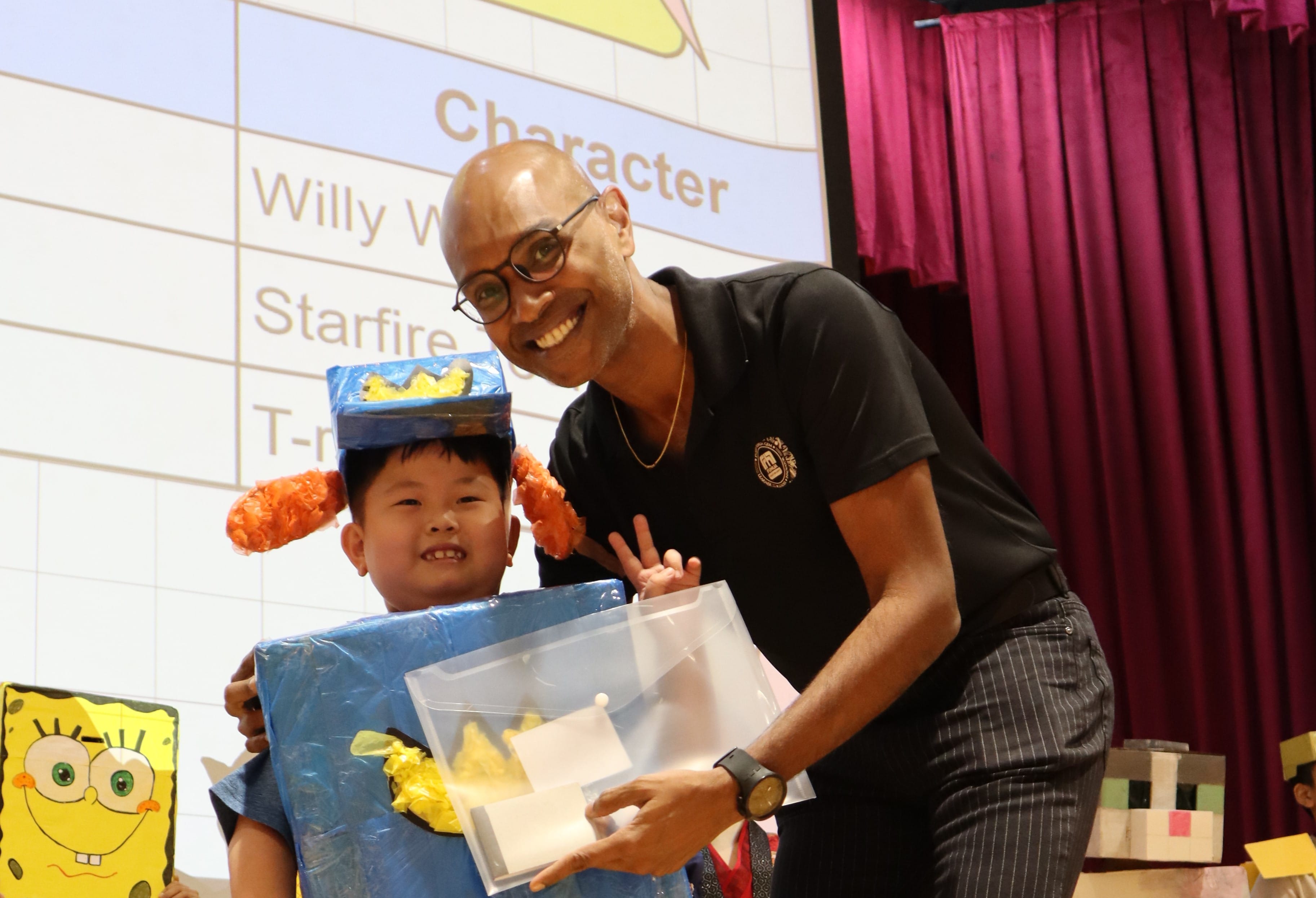 Fuhua's principal, Mr Ganesan, poses with a student wearing a handmade blue cardboard costume at a school event.