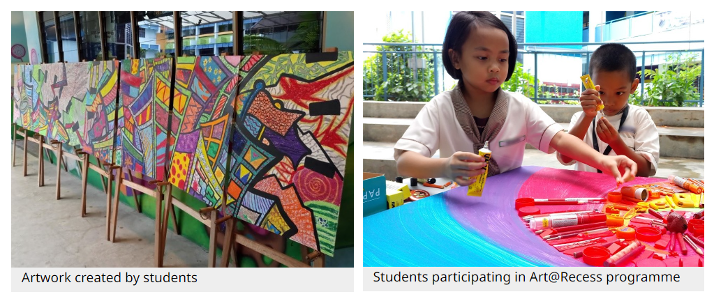 Colorful student artworks on easels beside two children painting at a table with art supplies.