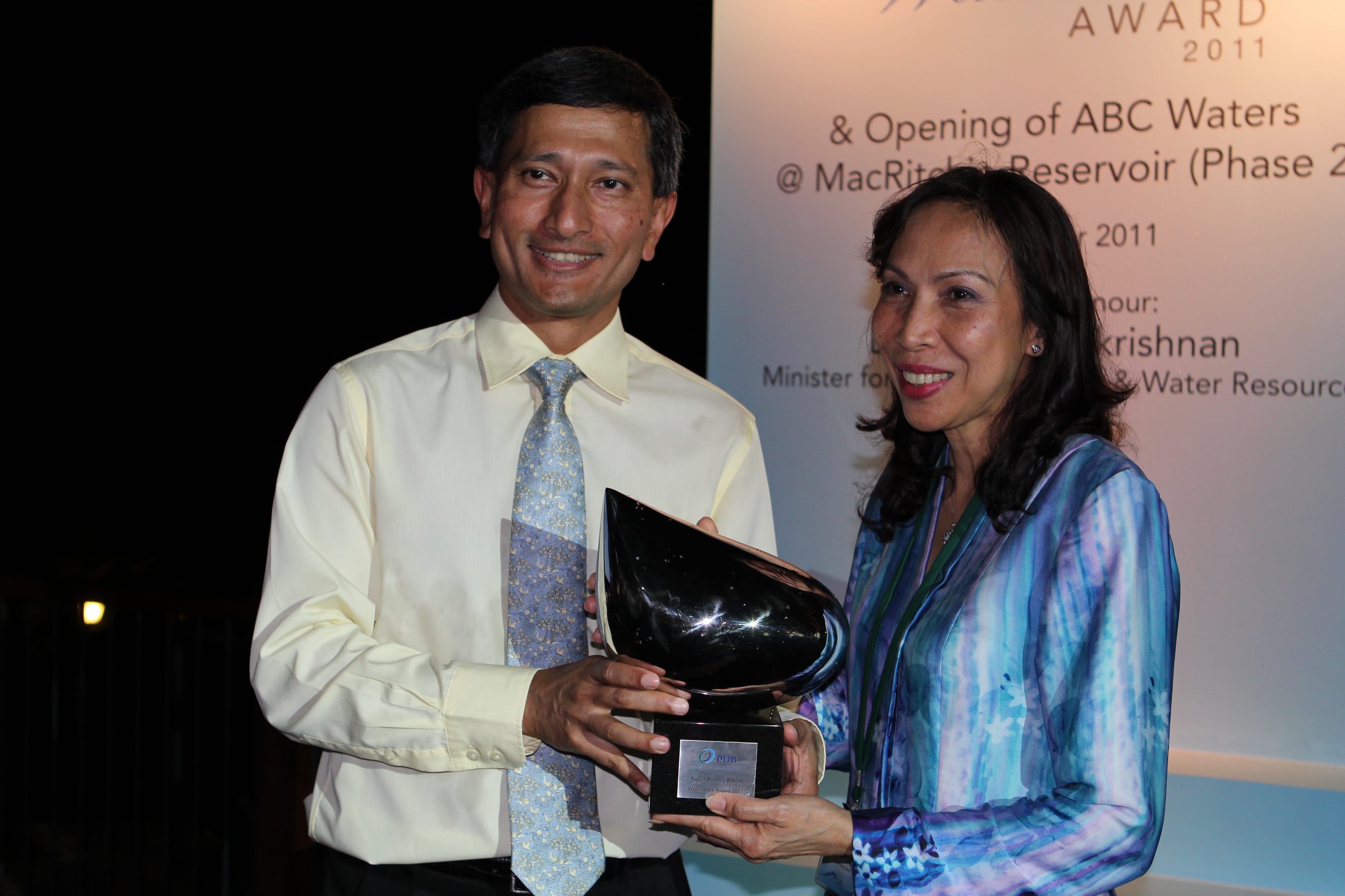 Two people smile while jointly holding a dark trophy at the 2011 ABC Waters Award ceremony.