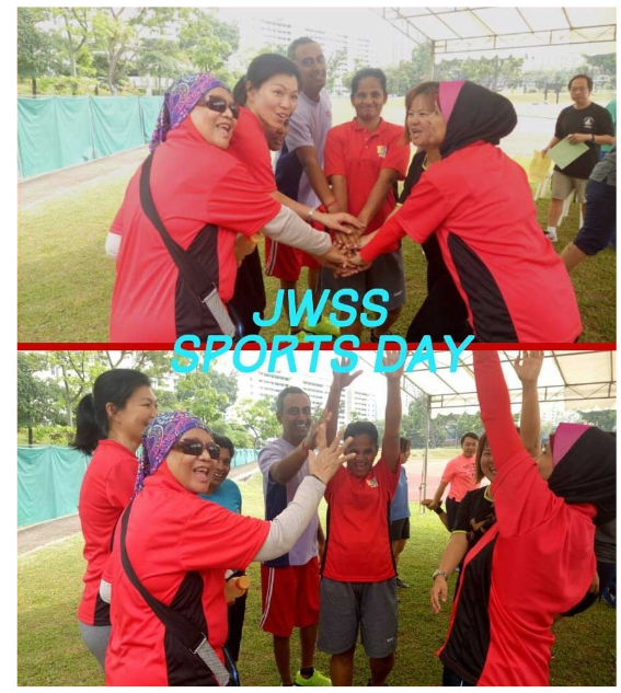 Group of people in red shirts joining hands and cheering outdoors at JWSS Sports Day event.