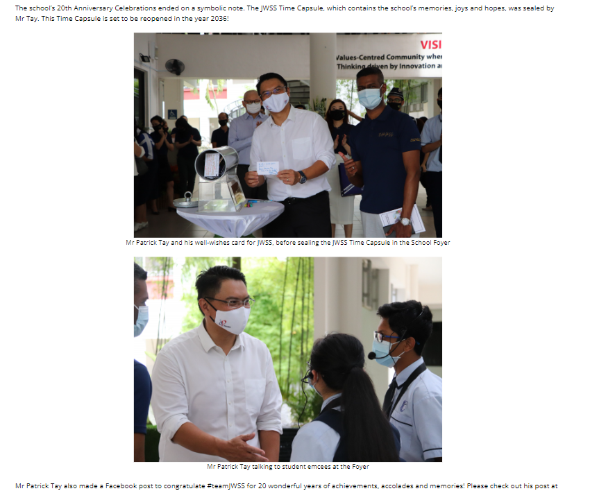 Man in white shirt and mask holds a card near a time capsule, with a group of masked people nearby.