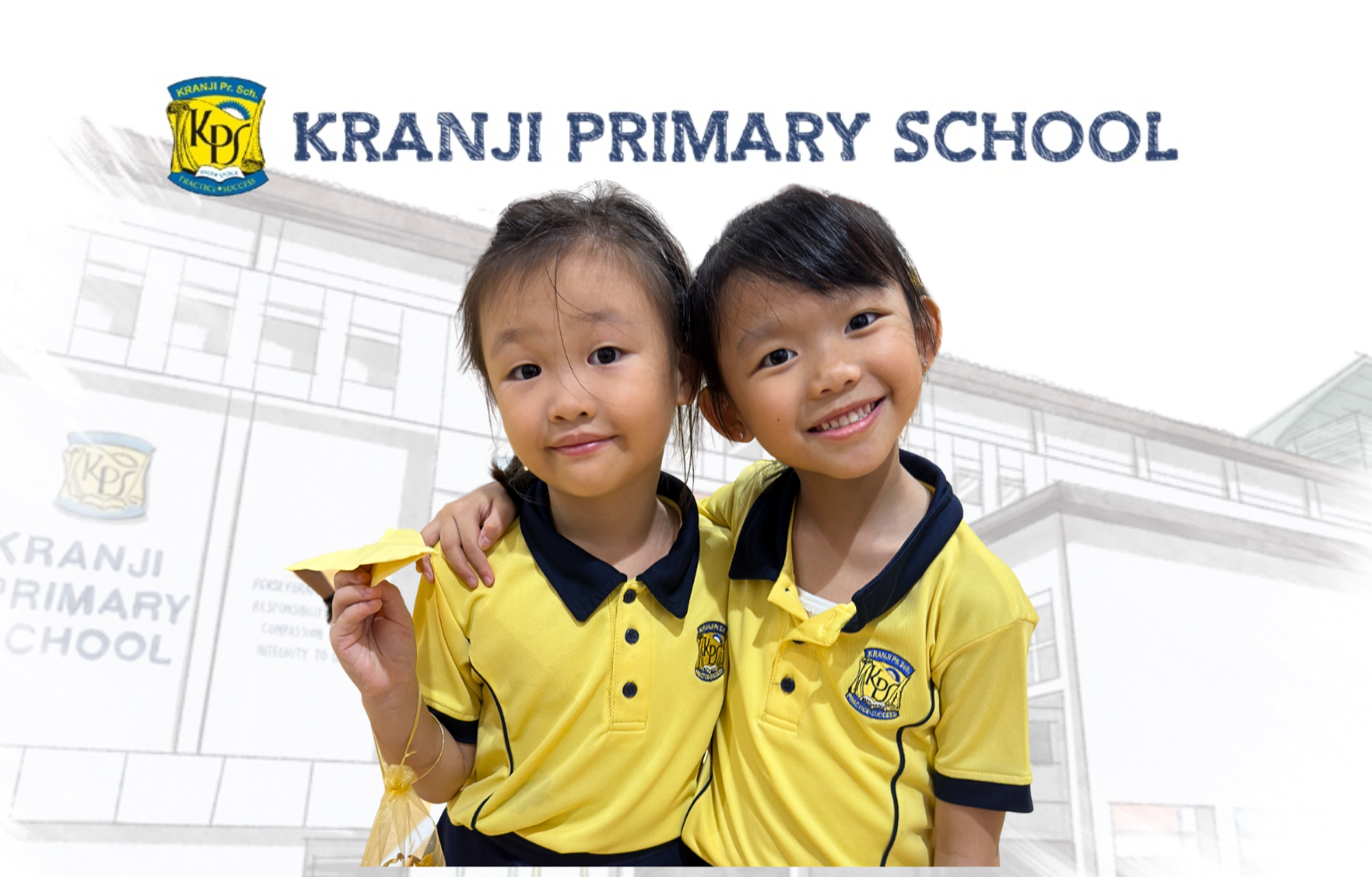 Two smiling girls in Kranji Primary School yellow uniforms pose together, one holding a paper plane.