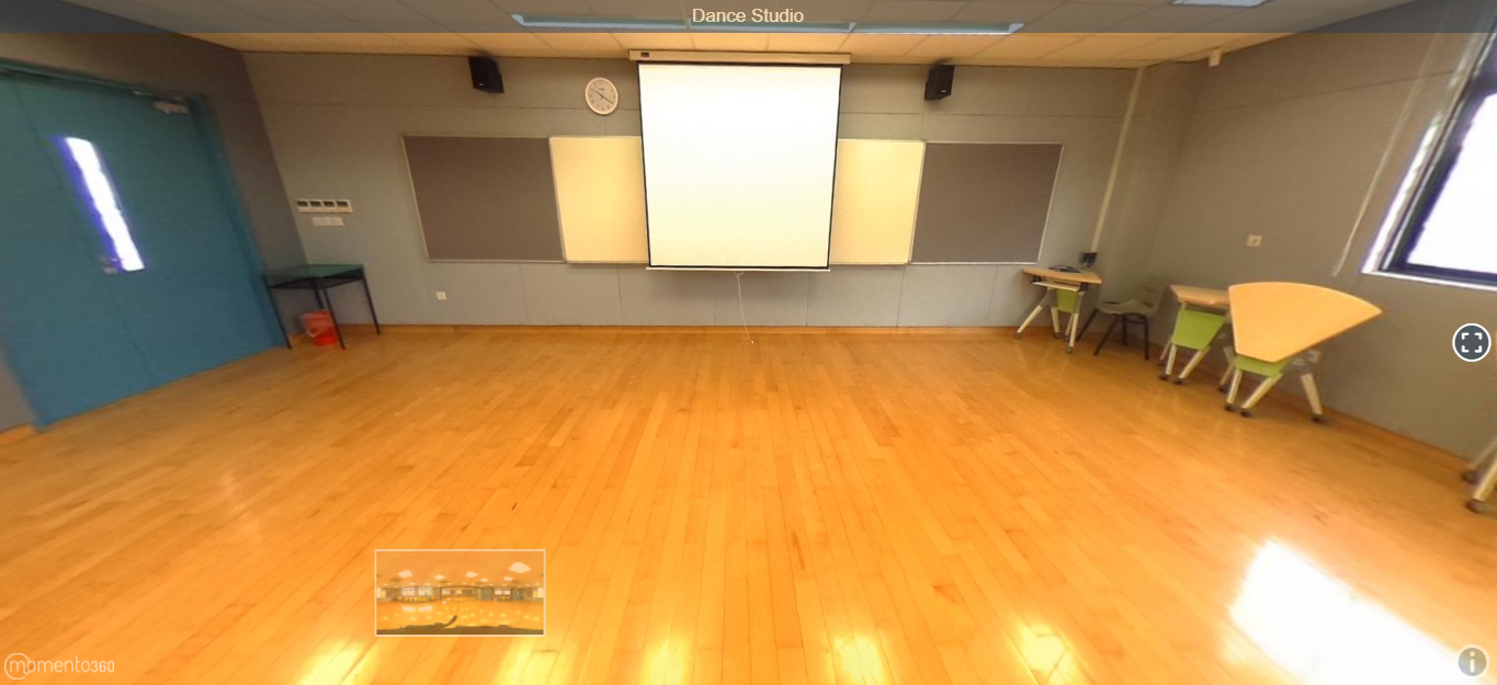 Empty dance studio with wood floor, projection screen on gray wall, whiteboards, clock, and chairs on the right.