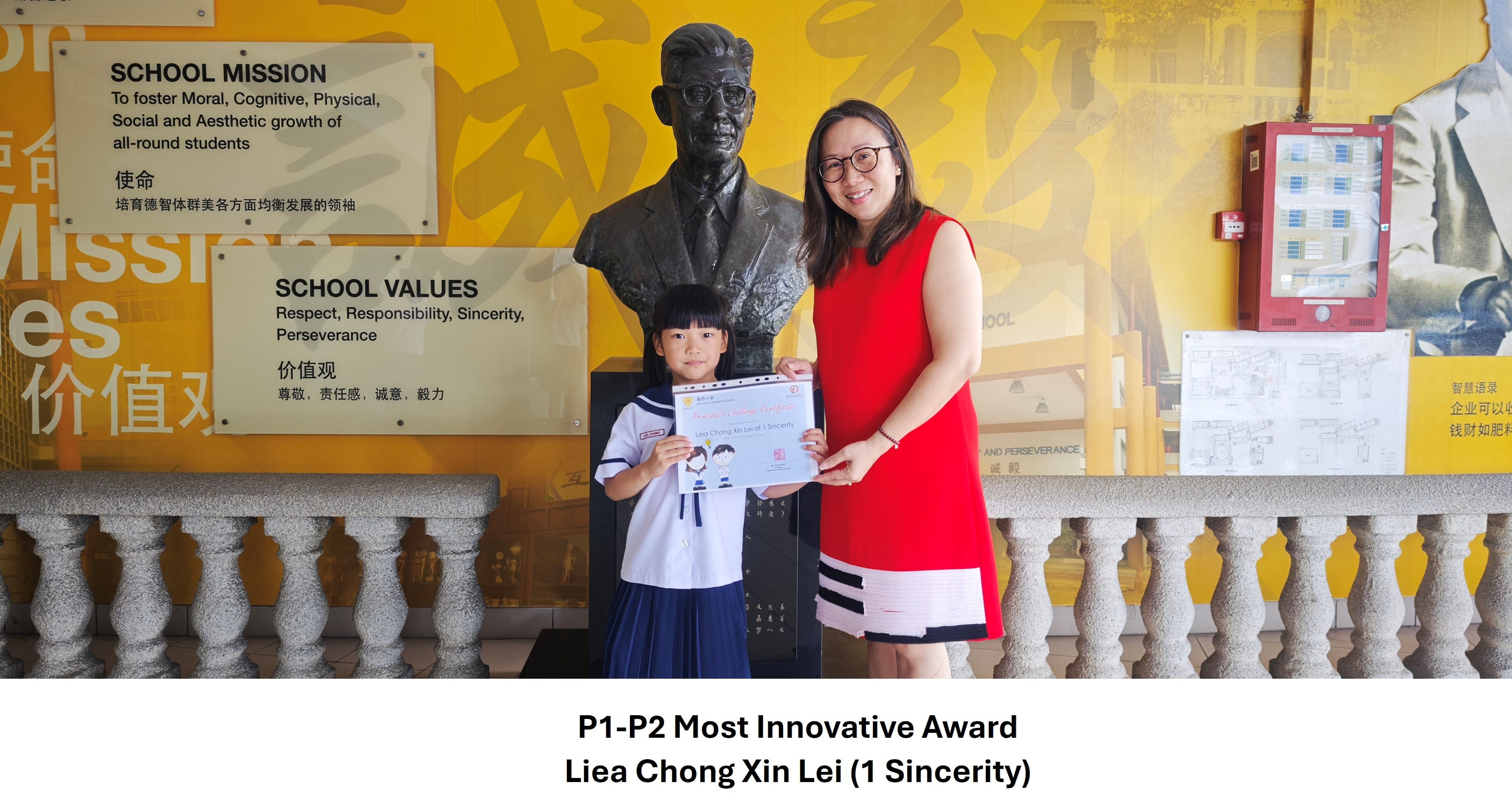 Young girl in school uniform holds an award certificate beside a woman in red, standing before a bronze bust at school.