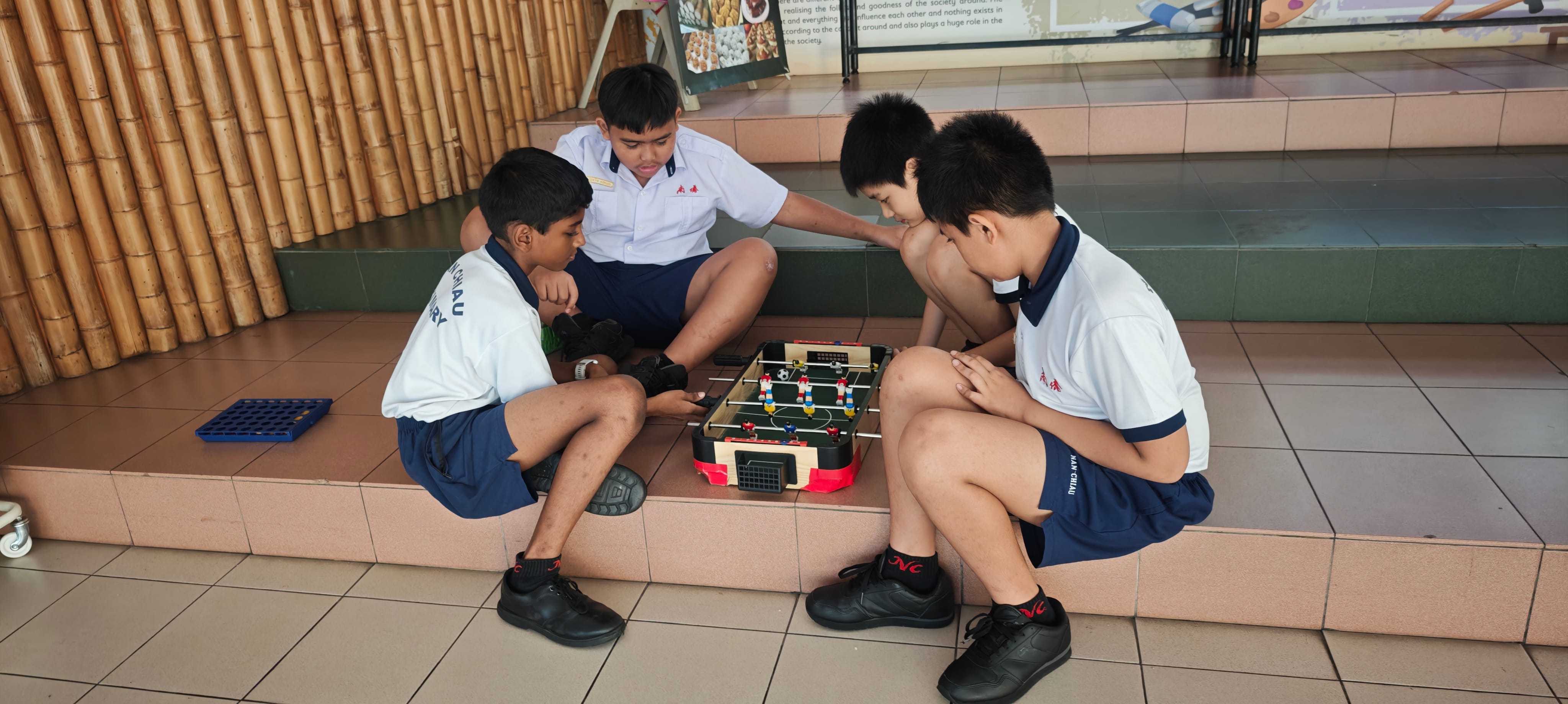 PSLs and students playing a small tabletop foosball game.
