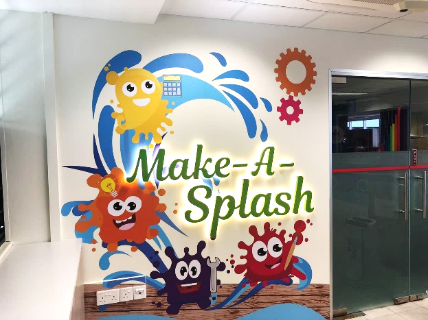 Colorful wall mural reading Make-A-Splash with cartoon blob characters, water waves, and gear decorations.