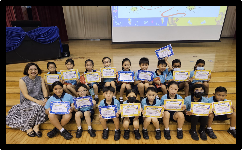A teacher and group of young students sit on wooden steps holding blue and gold Star Reader certificates.