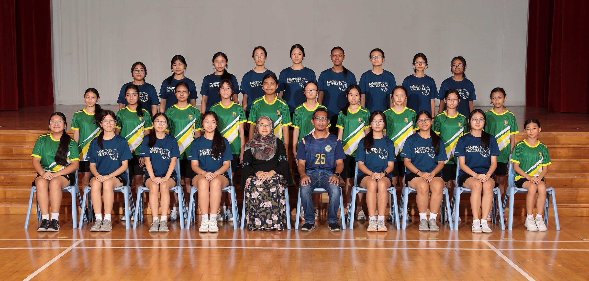 Group photo of Tampines Netball team members in green and navy jerseys, posed in three rows with two coaches seated.