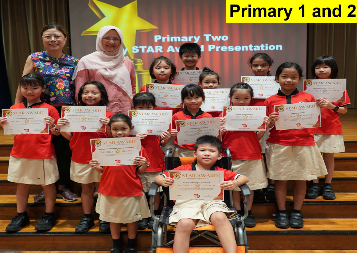 Primary 1 and 2 students in red uniforms holding Star Award certificates, posed with two teachers on a stage.