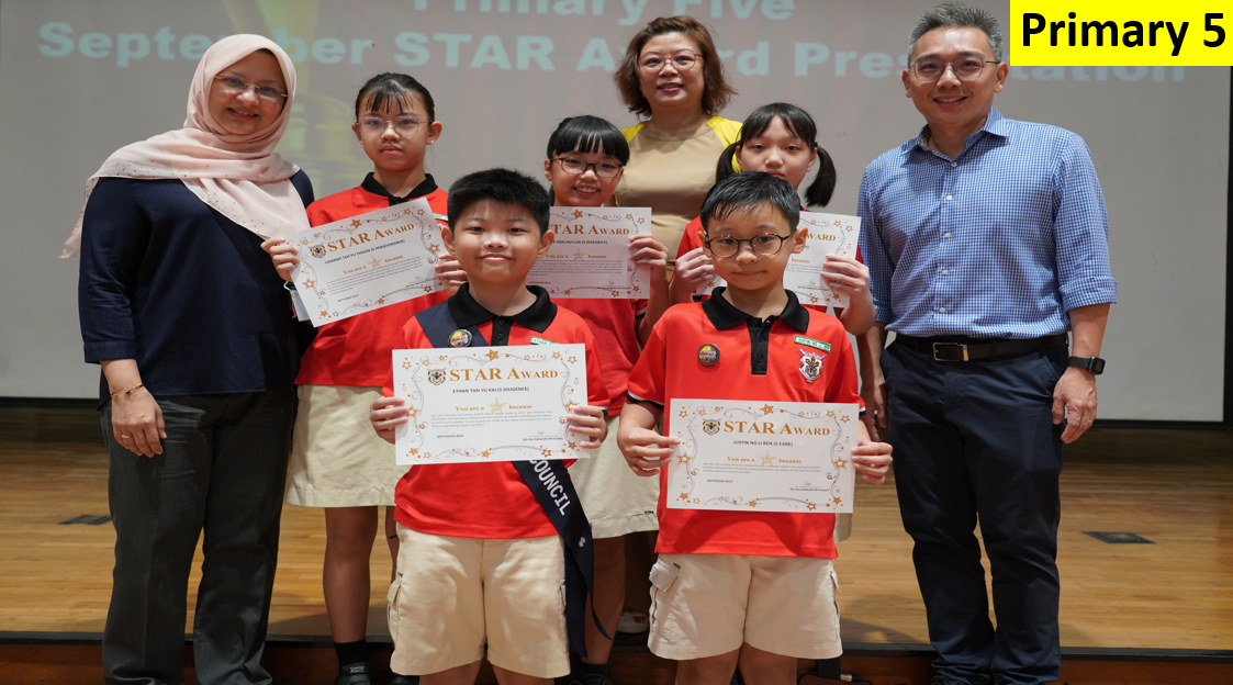 Five children in red uniforms hold STAR Award certificates, flanked by two adult teachers at a Primary 5 award ceremony.