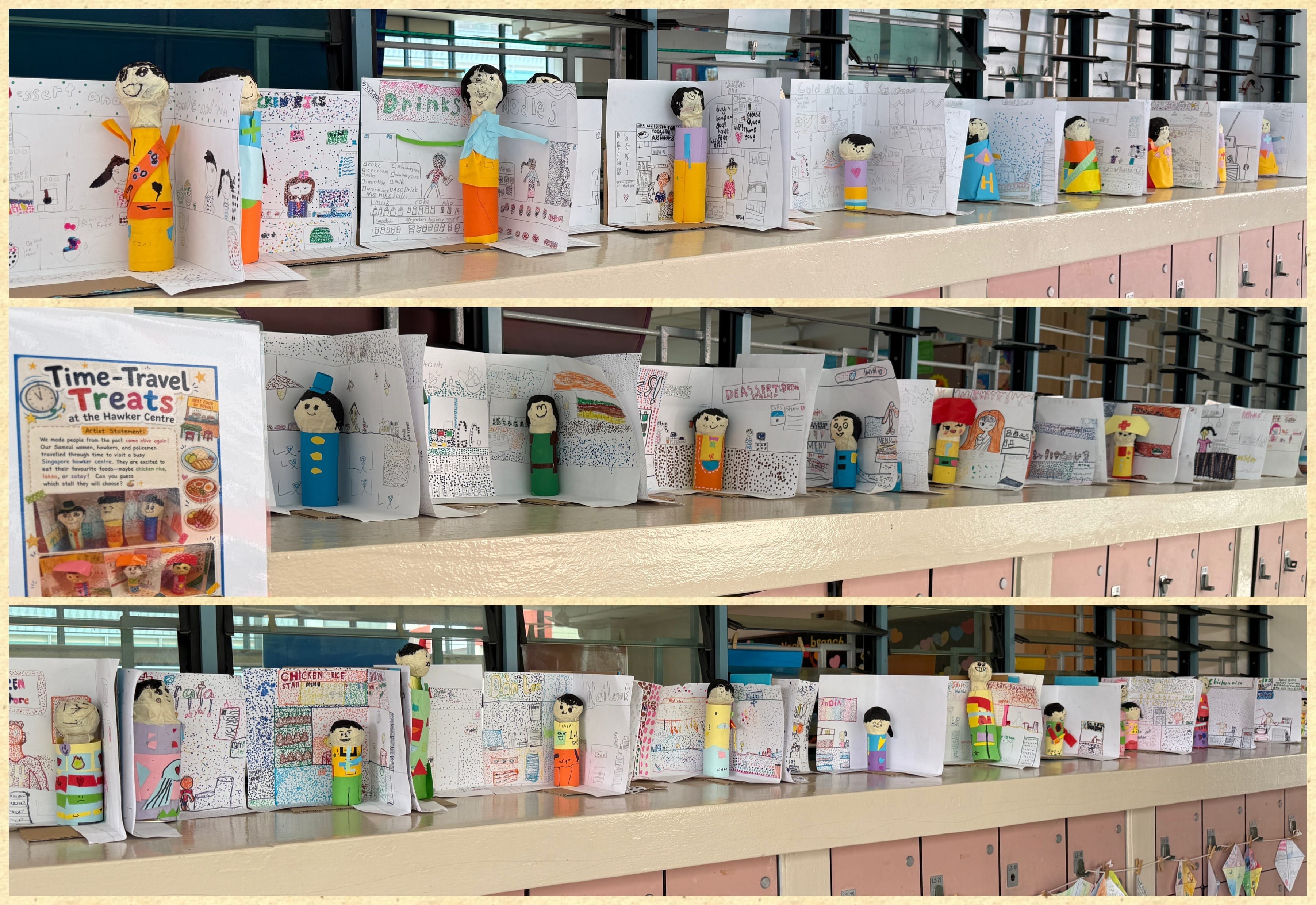 Rows of handmade paper booklets with colorful drawings, each propped open by a small paper doll figure.