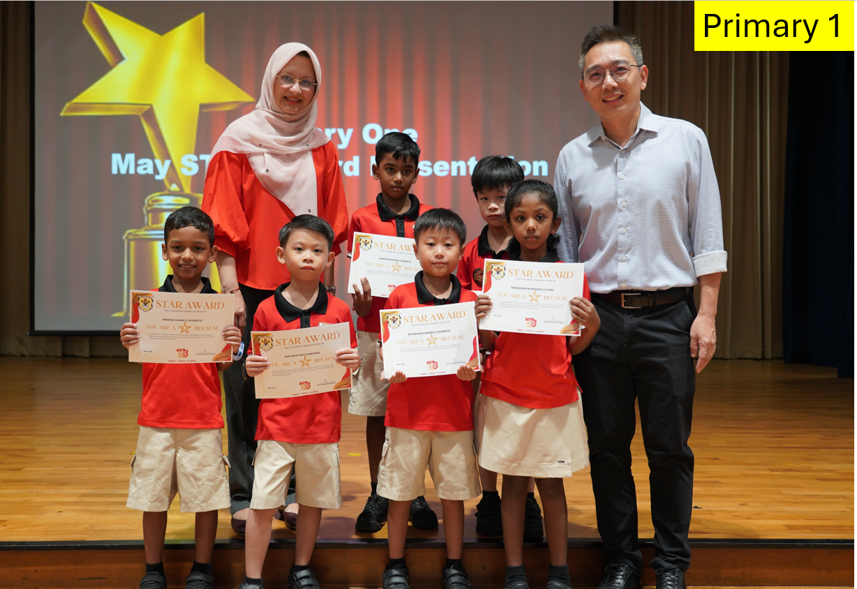 Two adults and five young students in red uniforms holding Star Award certificates on a stage.