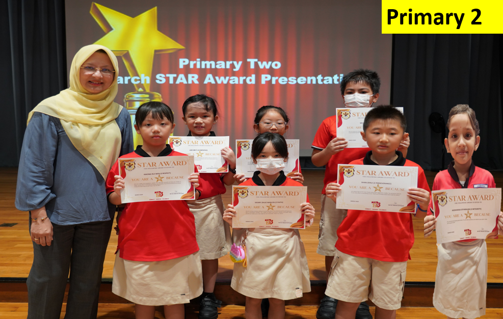 A teacher and six young students hold Star Award certificates at a Primary Two award presentation ceremony.