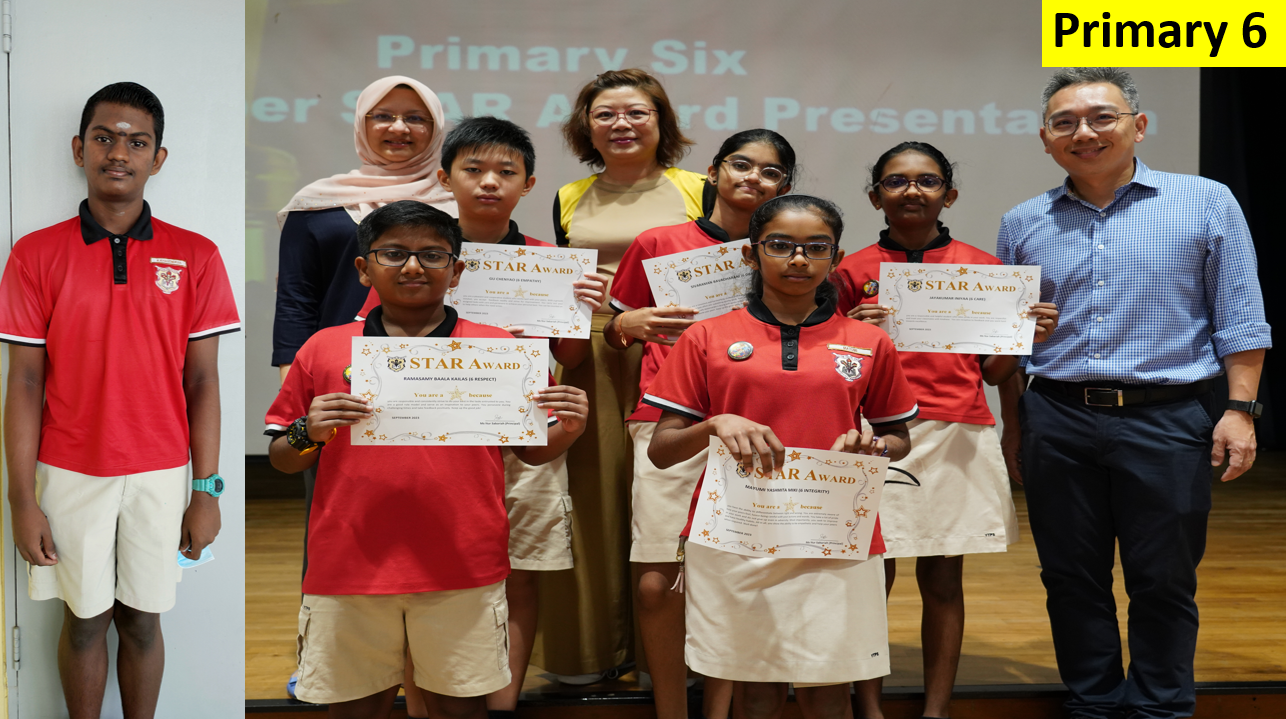 Primary 6 students in red uniforms hold Star Award certificates on stage with two adult presenters behind them.