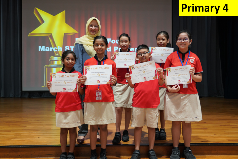Six Primary 4 students in red uniforms hold Star Award certificates, posing with a teacher on a stage.