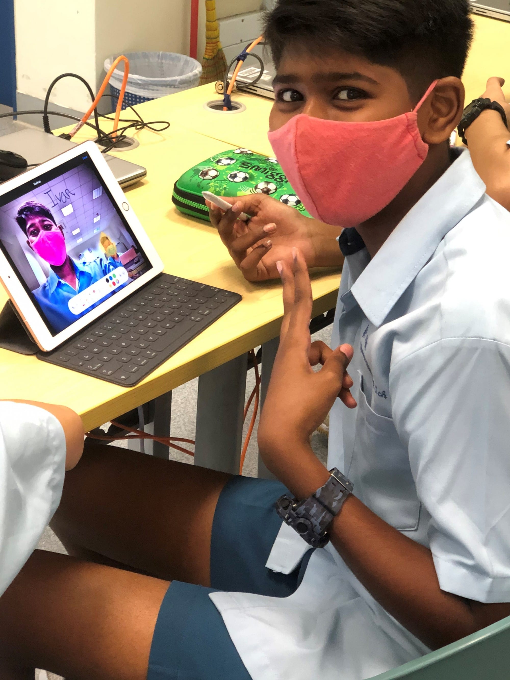 Student using a tablet in class to edit a selfie with digital drawing tools.