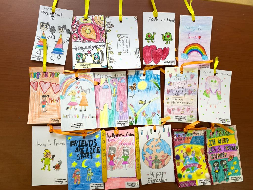 Colorful handmade bookmarks with drawings, hearts, rainbows, and friendship messages, tied with ribbons.