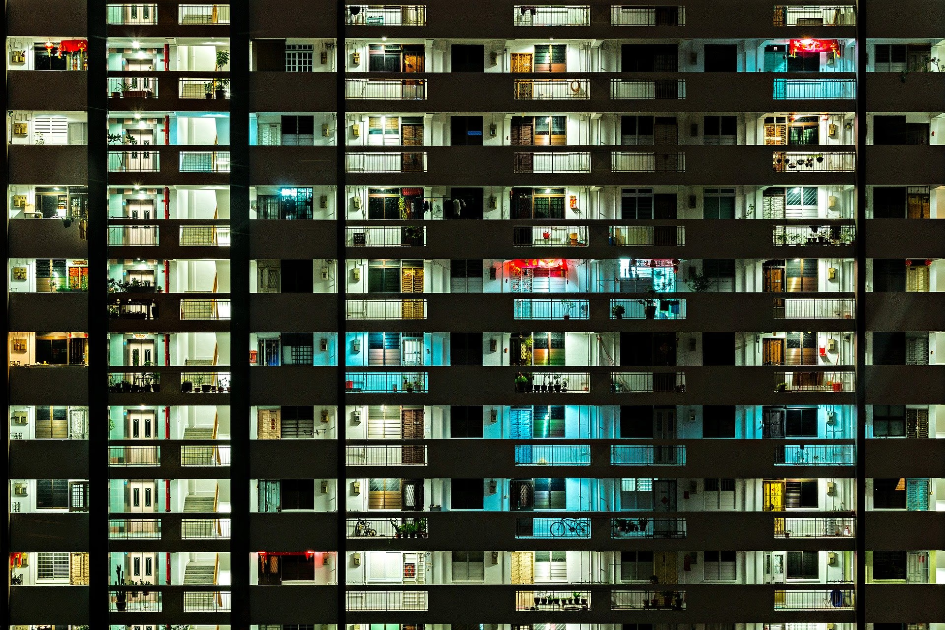 A HDB block at night, with lit corridors