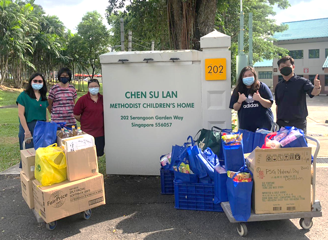 Four masked people stand with donation goods on carts outside Chen Su Lan Methodist Children's Home in Singapore.