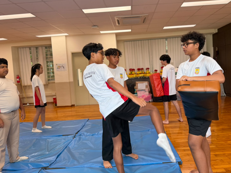 Students form the silat interest group teaching their batchmate how to perform a sidekick during the post-examination SIGMA workshop.