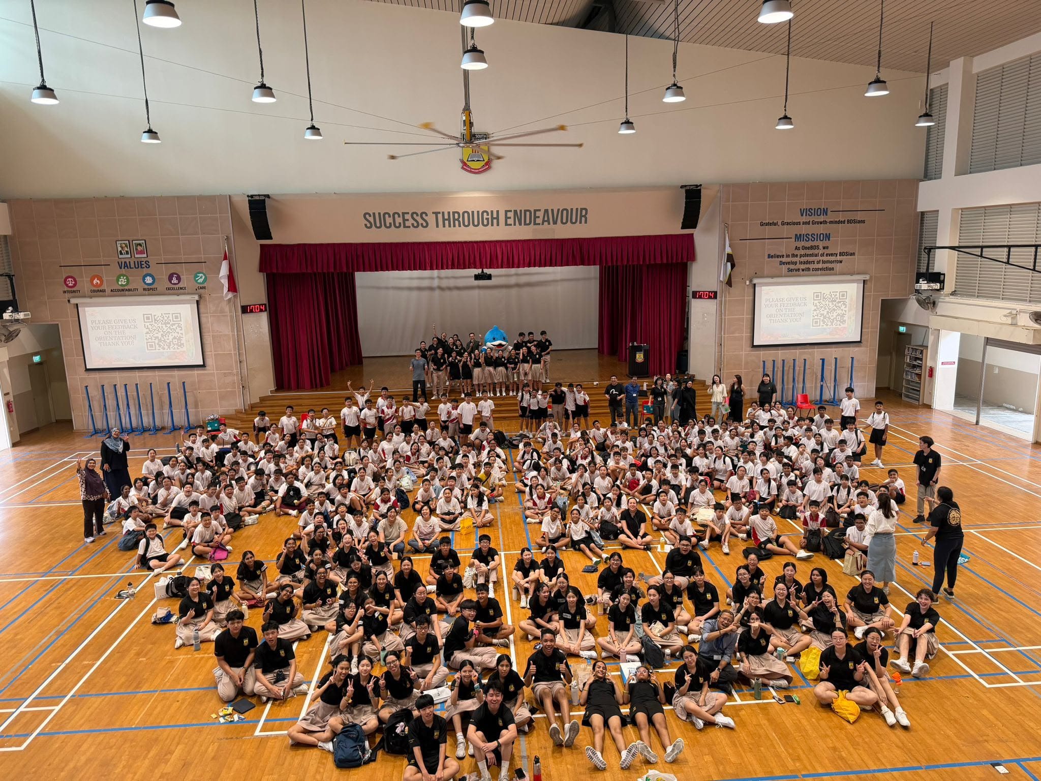A large cohort of BDS students assembled on the floor of the school hall during a level-wide event or camp.
