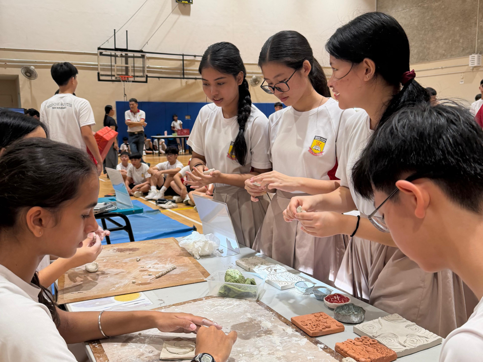 Students from the ceramics interest group teaching their peers how to mould clay at the Passion Day exhibition.