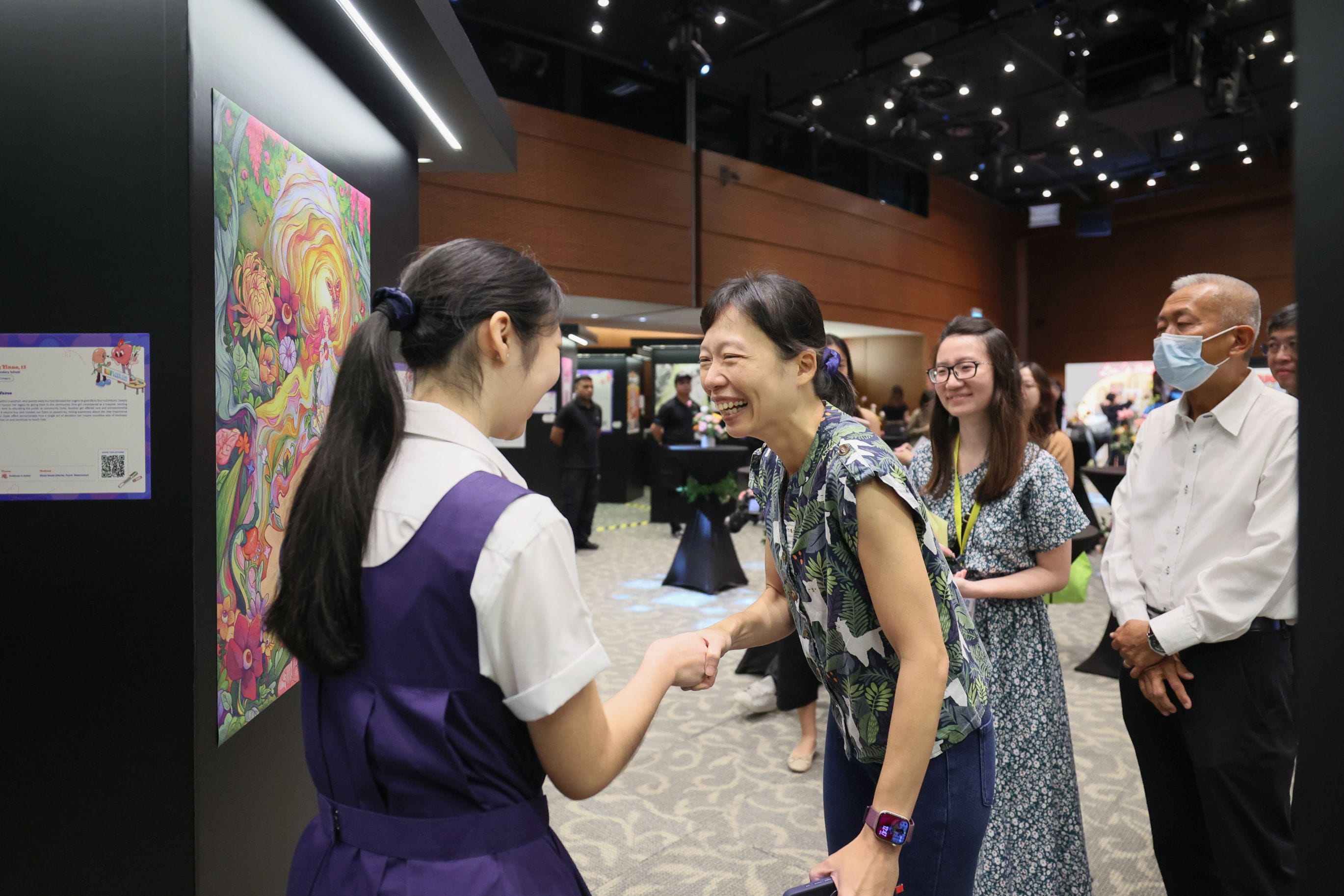 A student beside her winning artwork interacting with the guest-of-honour