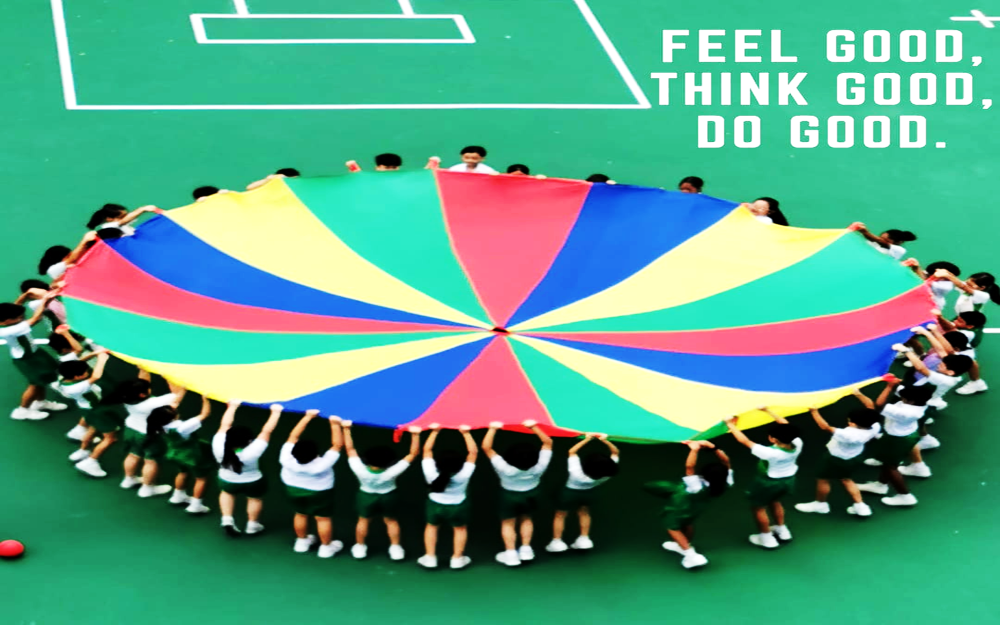 Children in uniforms stand in a circle holding a large colorful parachute on a green court.