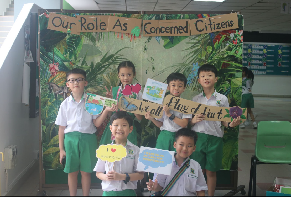 students posing at a photo booth , holding place cards