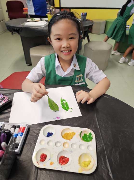 student showing art work using a leaf imprinted to a drawing block