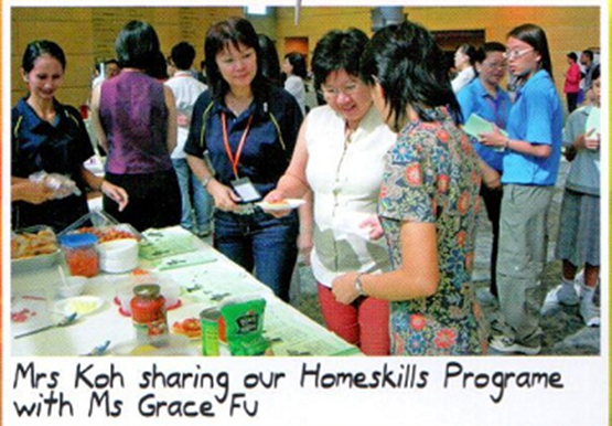 The principal sharing information about the Home Skills Programme with Minister Grace Fu at an exhibition booth.
