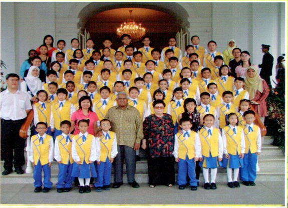 School brass band members and teachers posing for a commemorative group photo.