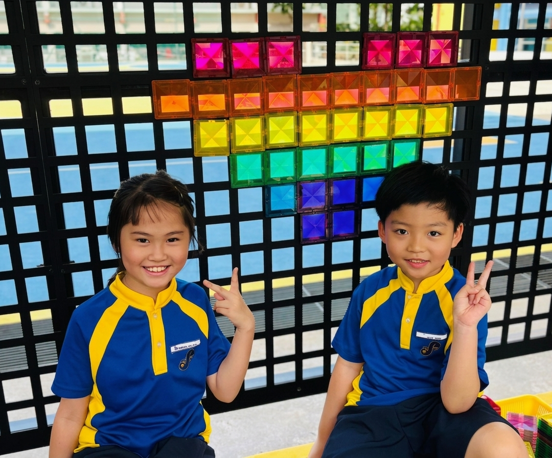 Two students posing in front of a colourful heart display.