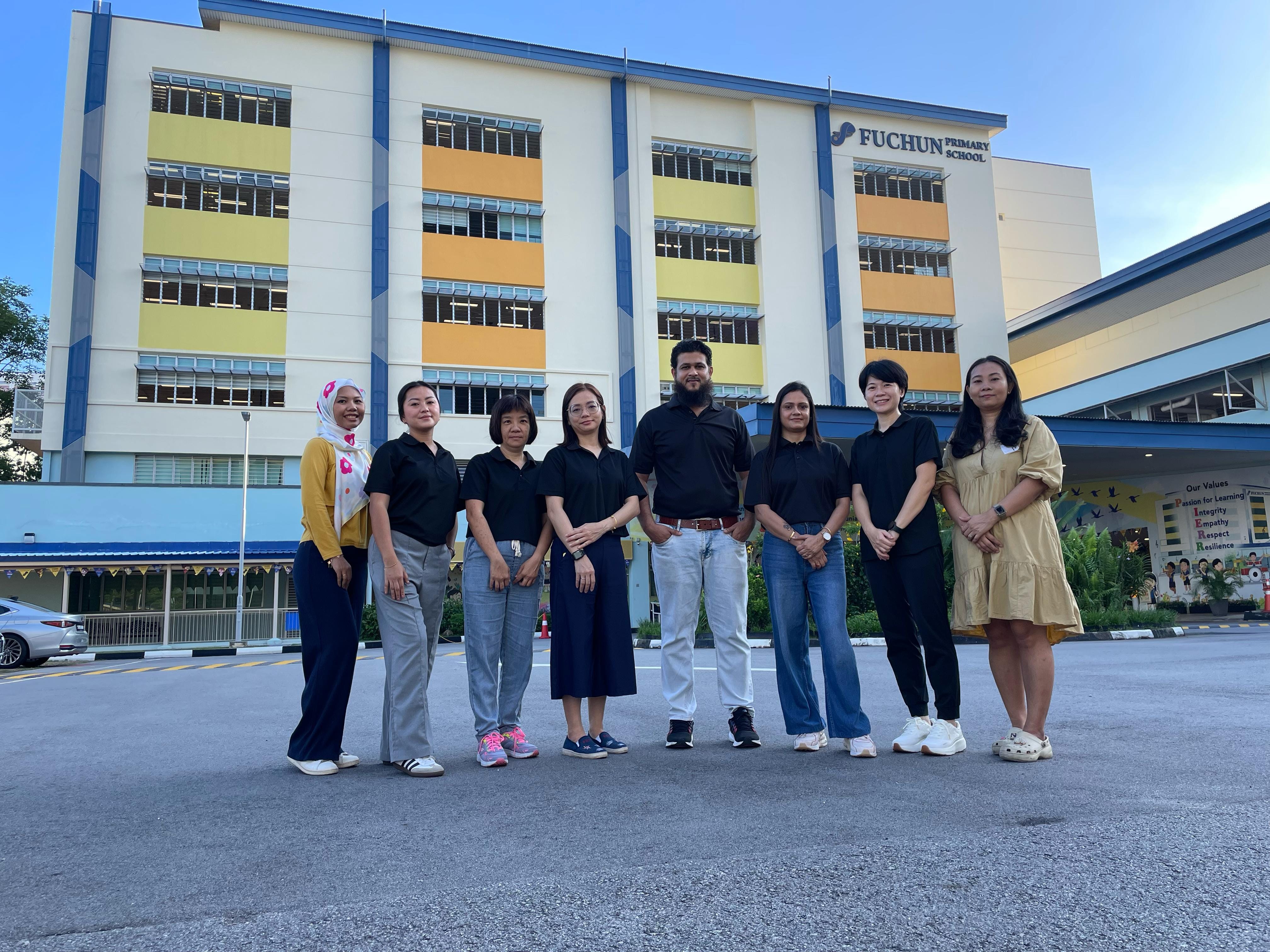 Members of the Fuchun Primary School Parents Support Group posing for a group photo in front of the school building.