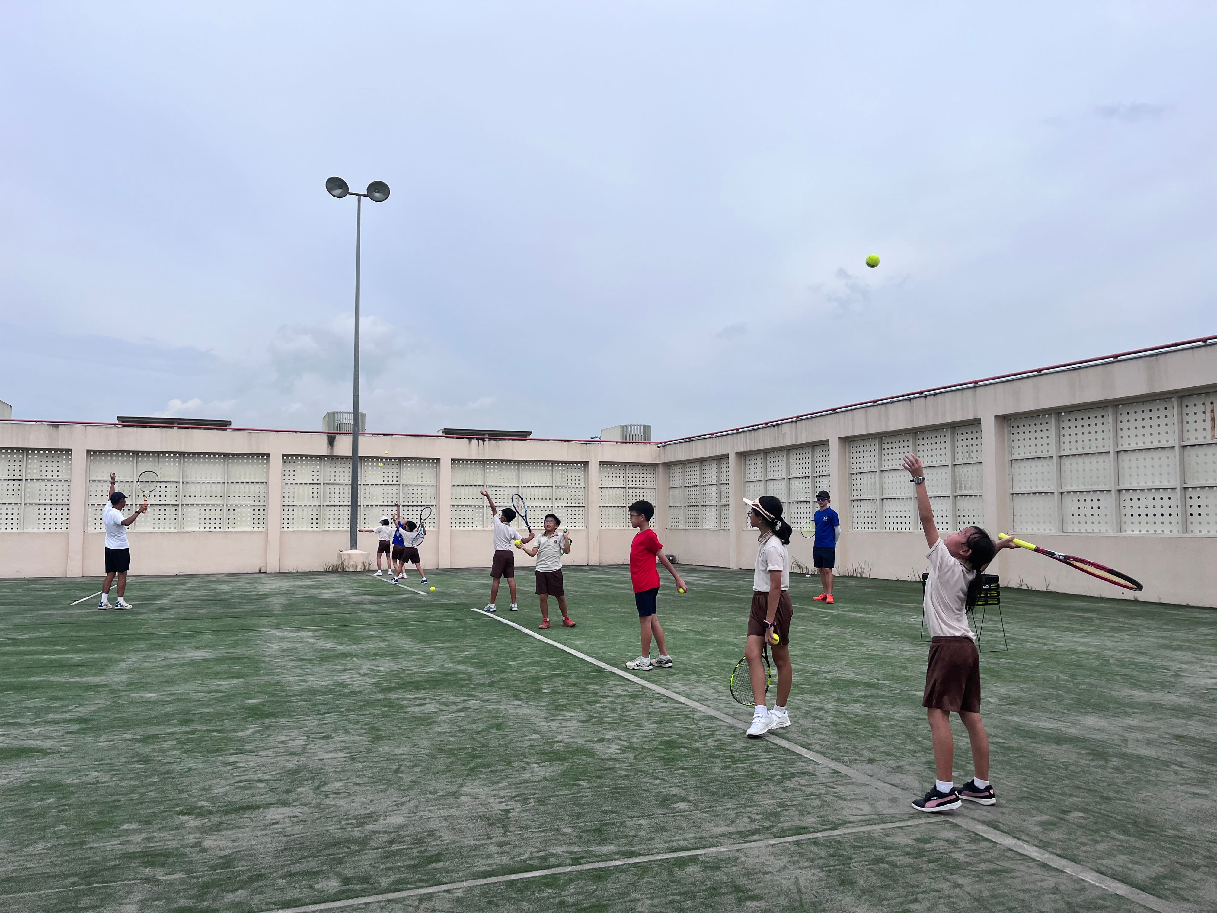 Tennis members practicing serves