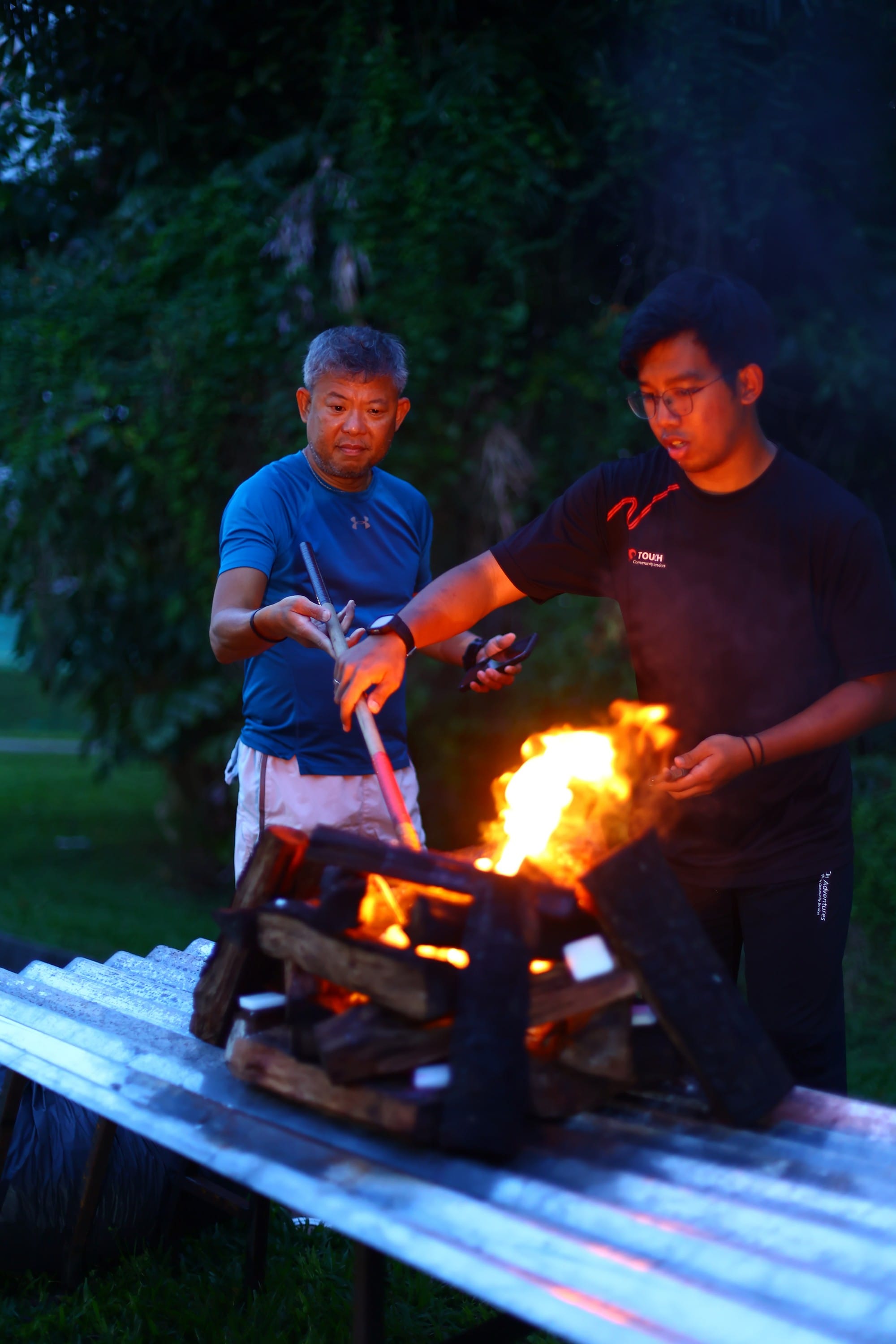 Mr Chua and a camp leader starting the campfire