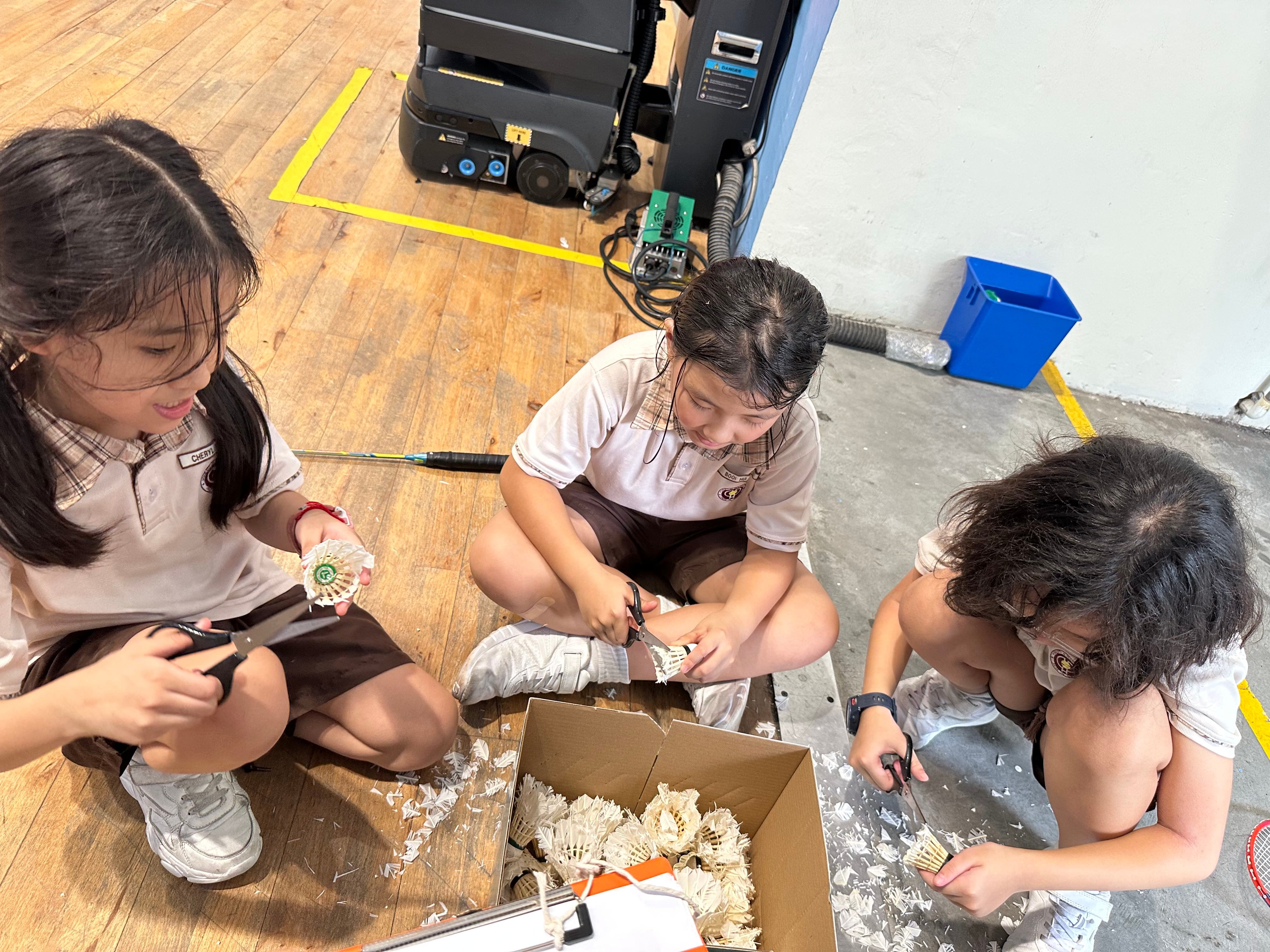 Students collecting and trimming used shuttlecocks as part of their VIA project