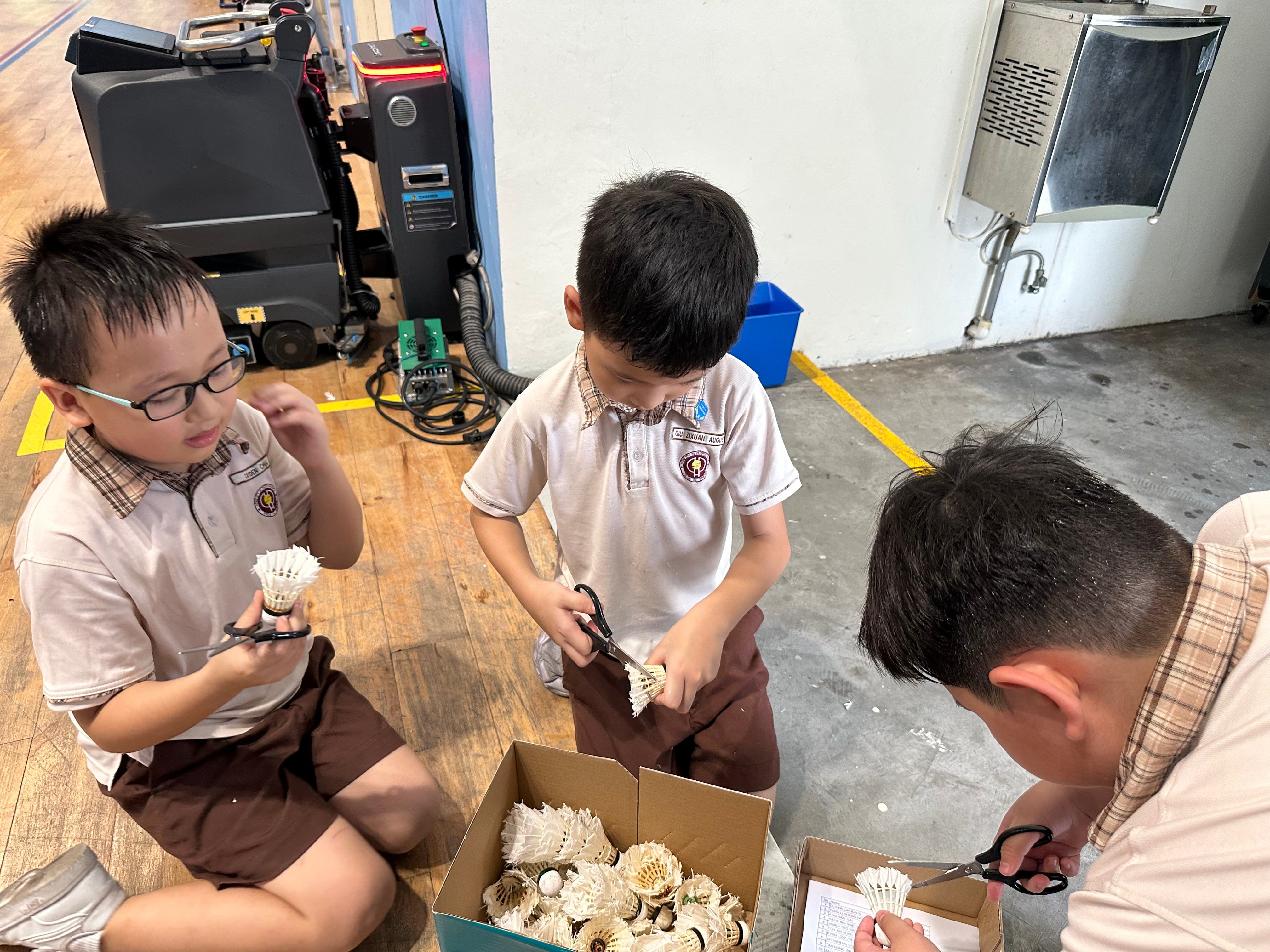 Students collecting and trimming used shuttlecocks as part of their VIA project
