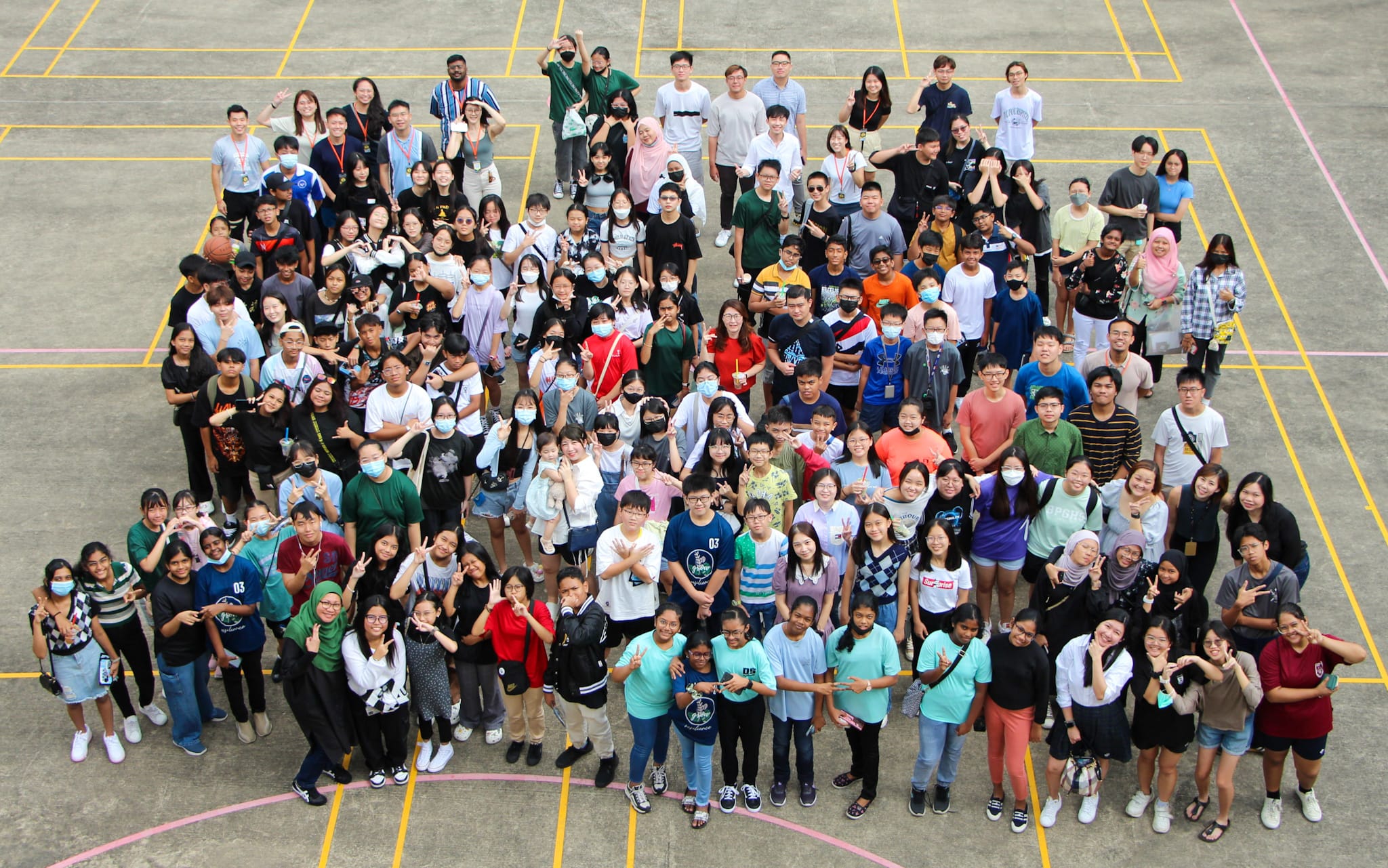 Large group of ex-students posing together on an outdoor court.