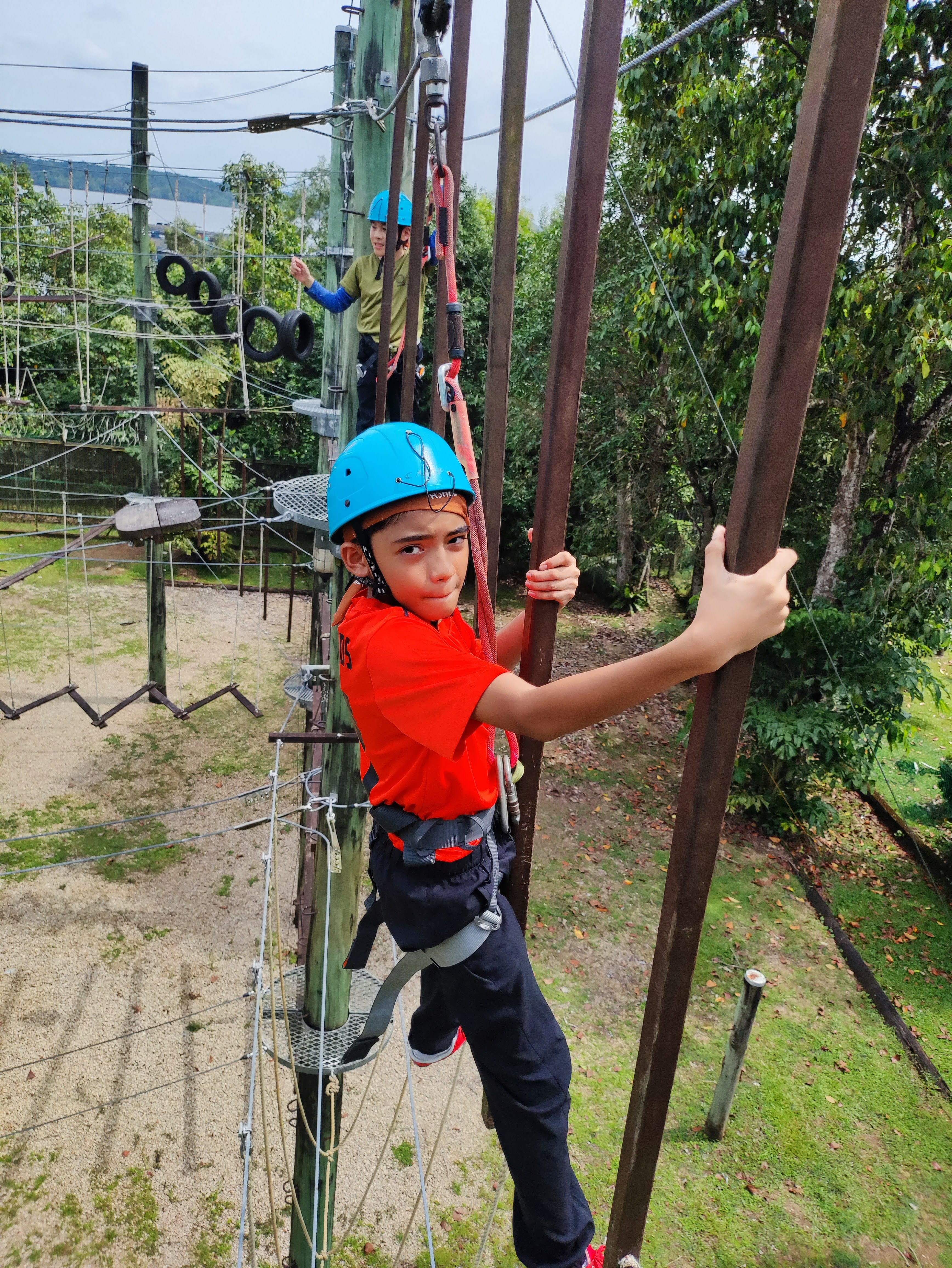 Student attempting an obstacle on a high element activity with safety gear.