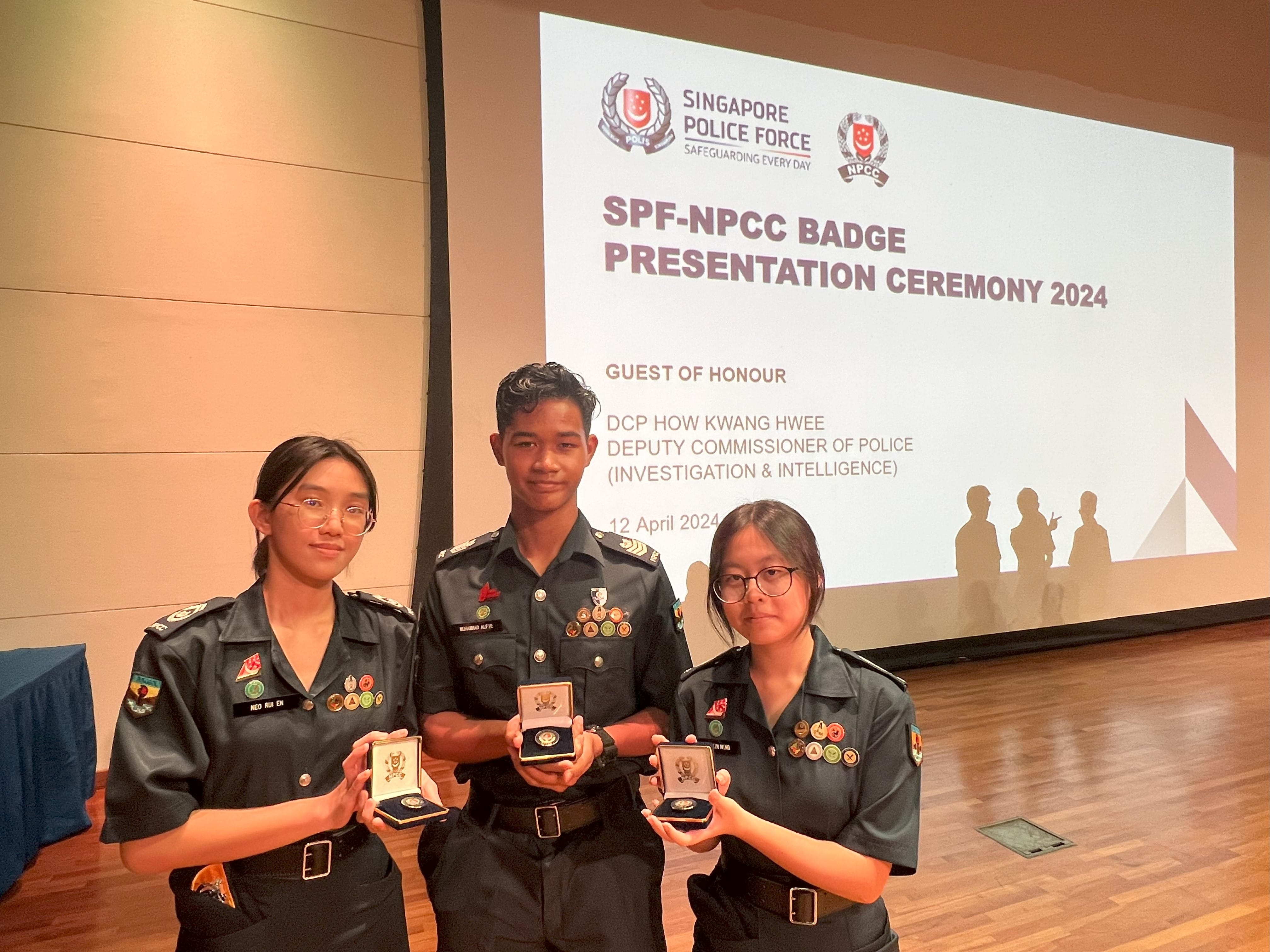 Three uniformed NPCC cadets hold medal boxes at the SPF-NPCC Badge Presentation Ceremony 2024 in Singapore.