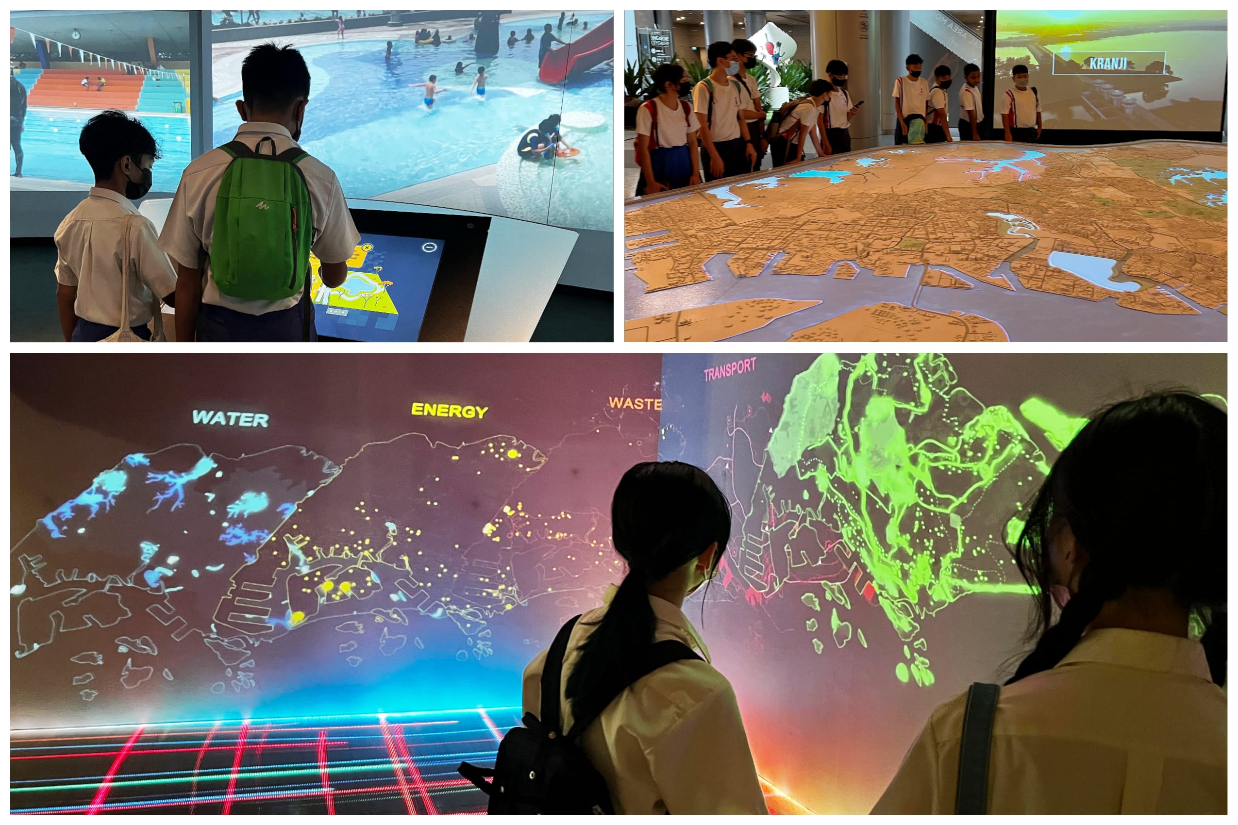 Students in uniforms view interactive maps and projections at an exhibit, including a large table map and wall display.