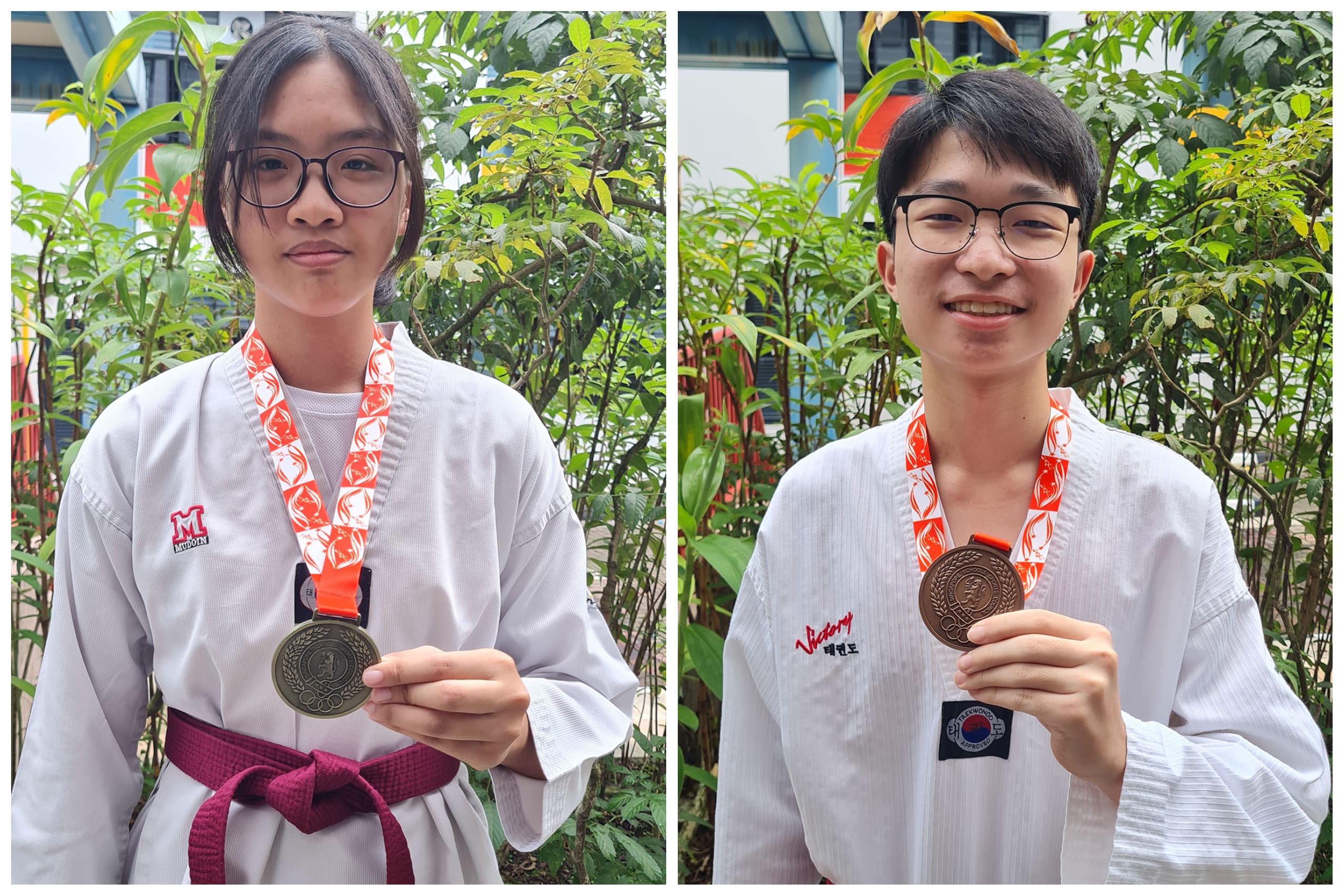 Two people in white martial arts uniforms hold medals on red ribbons, standing outdoors by green plants.