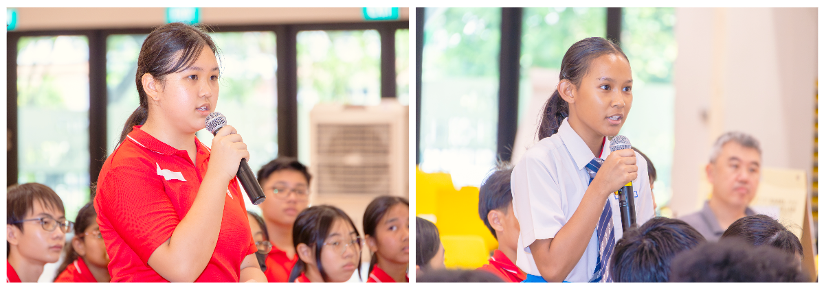 Two students speaking into microphones at a school event, one in a red shirt and one in a white uniform with a tie.