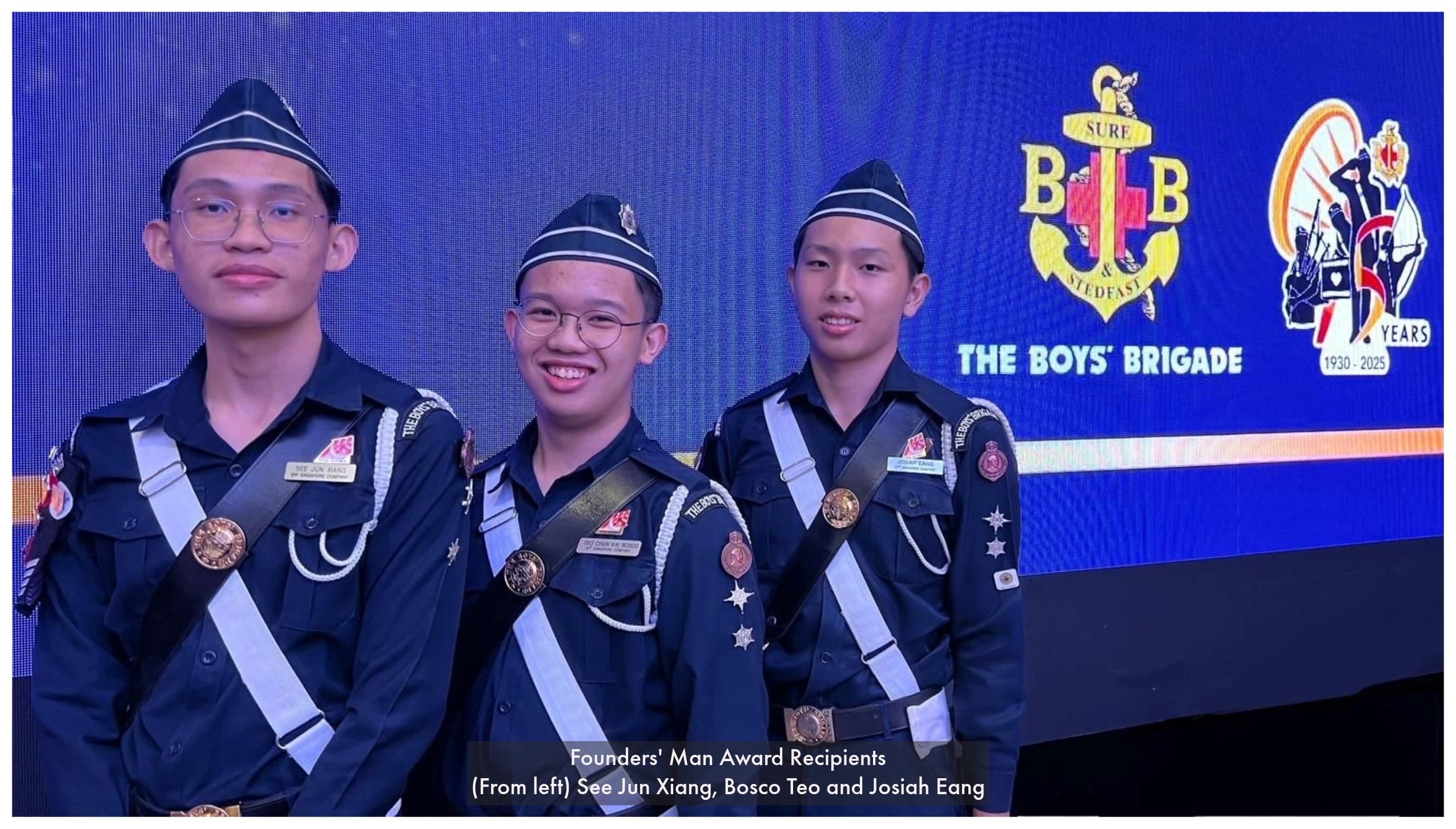 Three Boys' Brigade members in uniform pose before a blue backdrop marking the brigade's 1930-2025 anniversary.