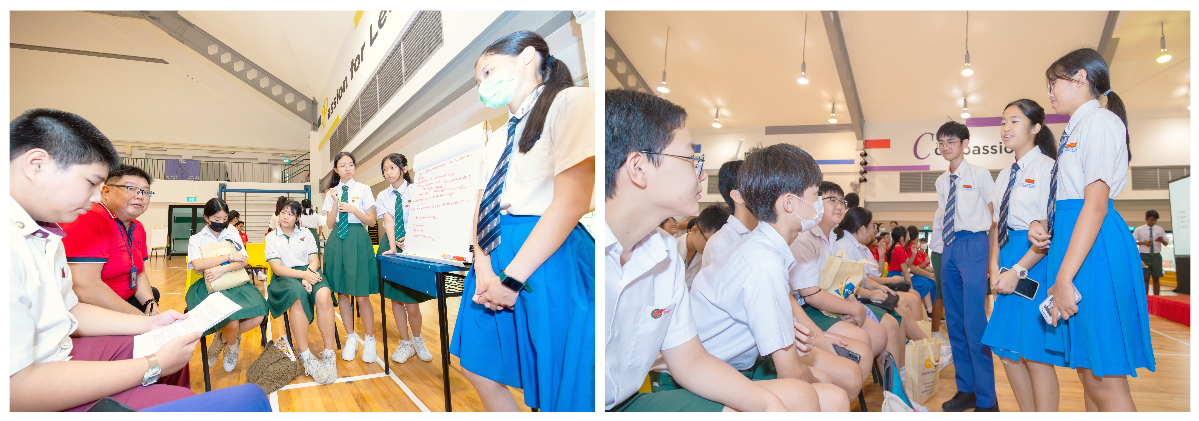 Students in school uniforms present to peers and judges in a school hall during an academic event.