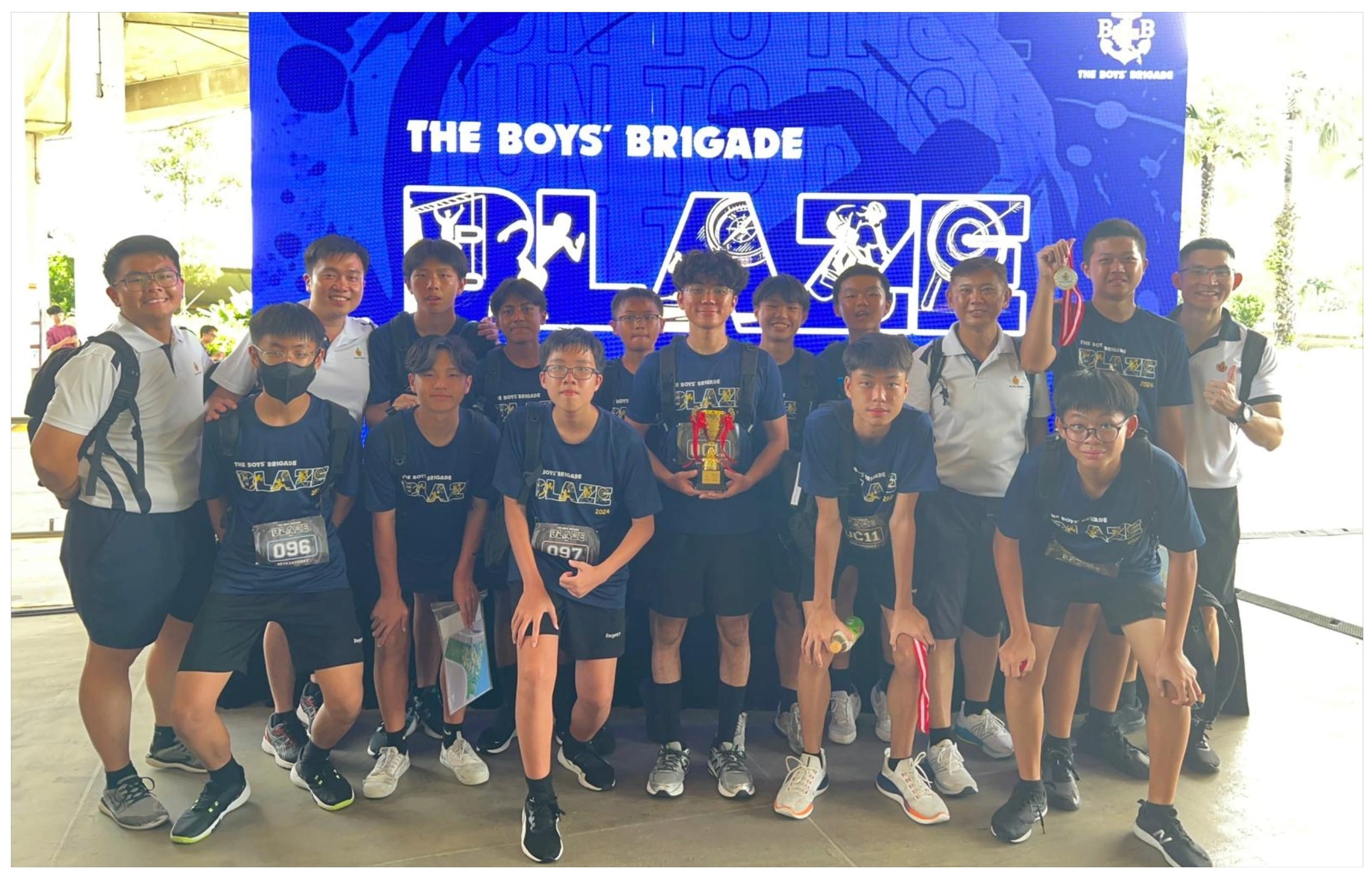 A group of boys in Blaze jerseys pose with a trophy in front of The Boys' Brigade Blaze blue backdrop.