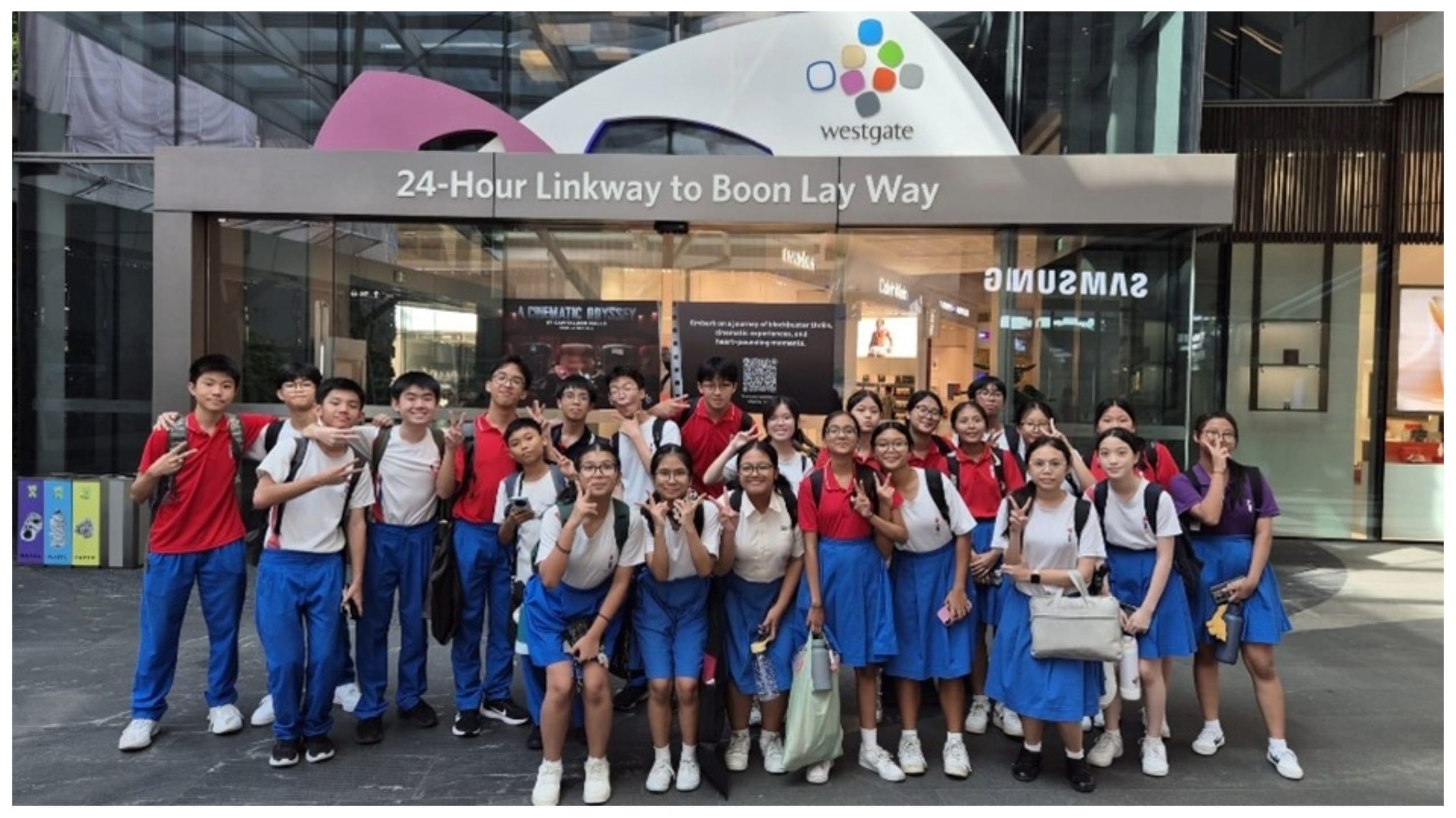 A group of students in uniforms posing outside Westgate mall's 24-Hour Linkway to Boon Lay Way entrance.
