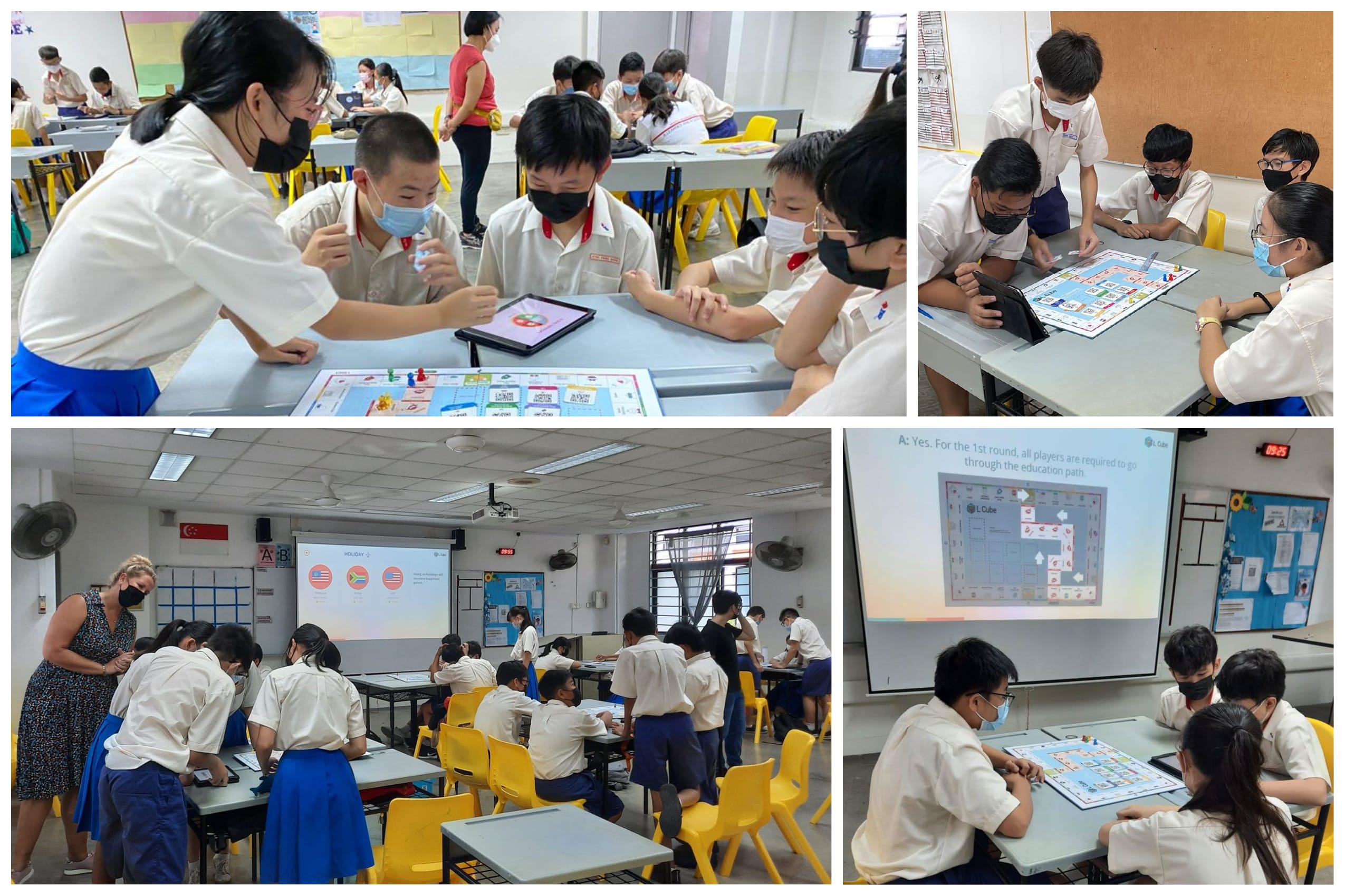 Students in school uniforms and masks play a board game in a classroom, guided by teachers with a projected screen.