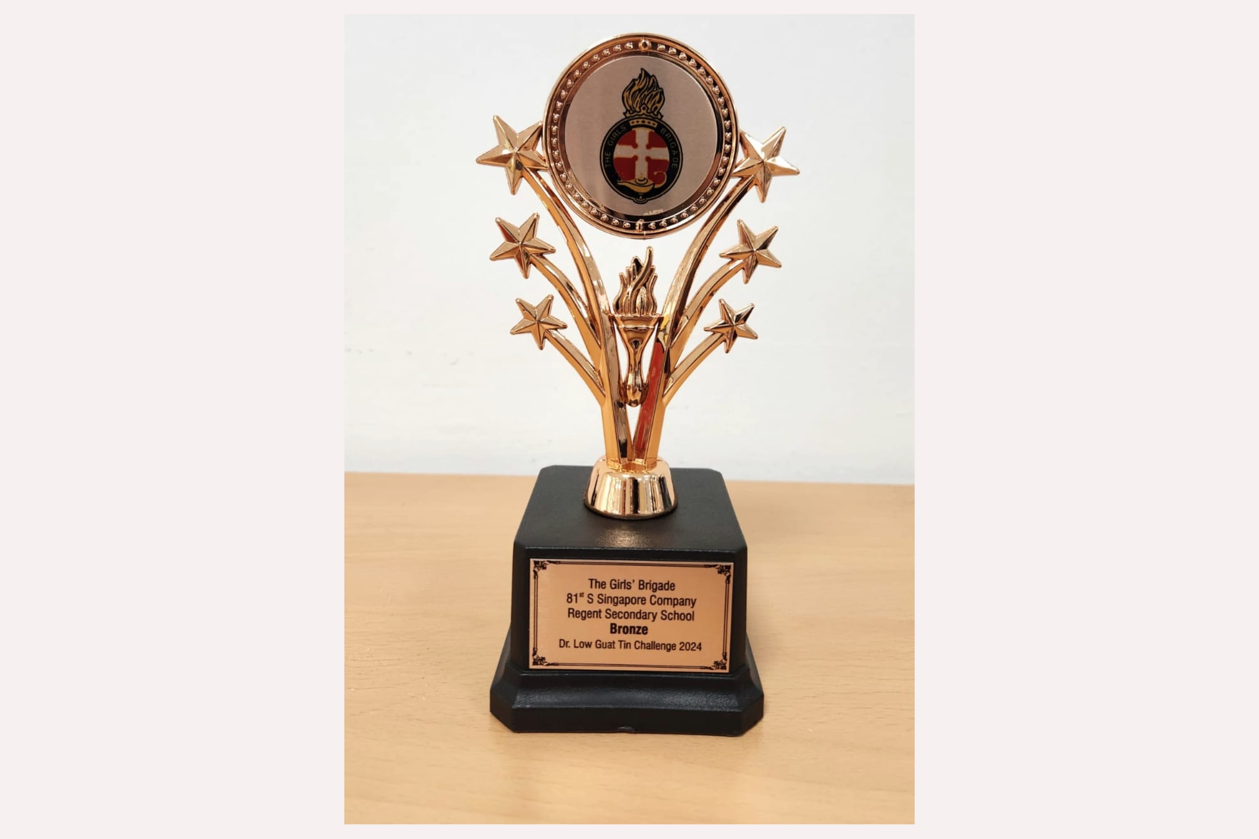 Gold trophy with stars and a circular emblem on a black base, inscribed with Girls' Brigade Bronze award 2024.